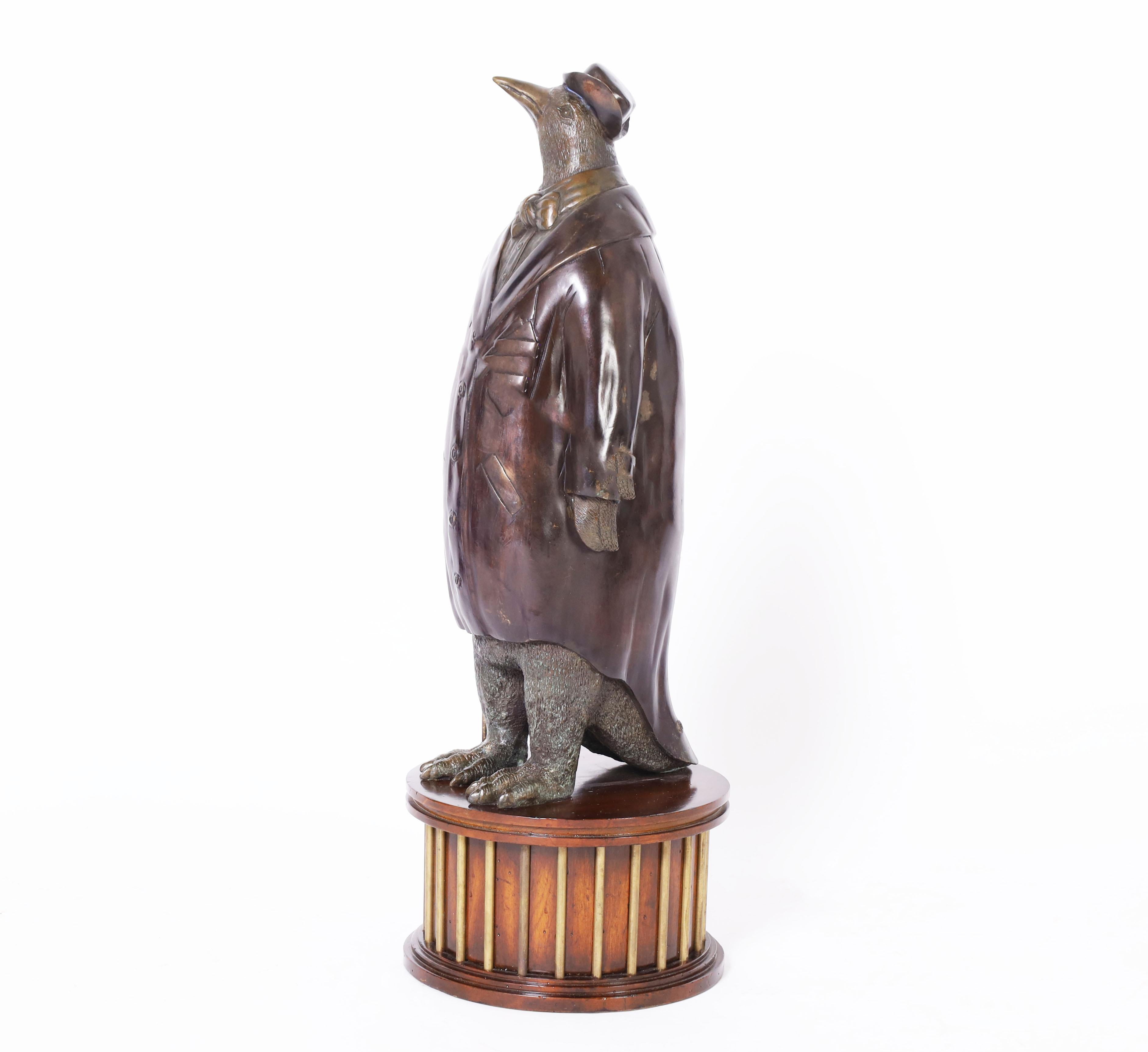 Striking mid century figural bronze sculpture of a penguin dressed in formal attire using three different patina techniques and presented on a mahogany and brass pedestal. Signed Maitland-Smith on the bottom.
