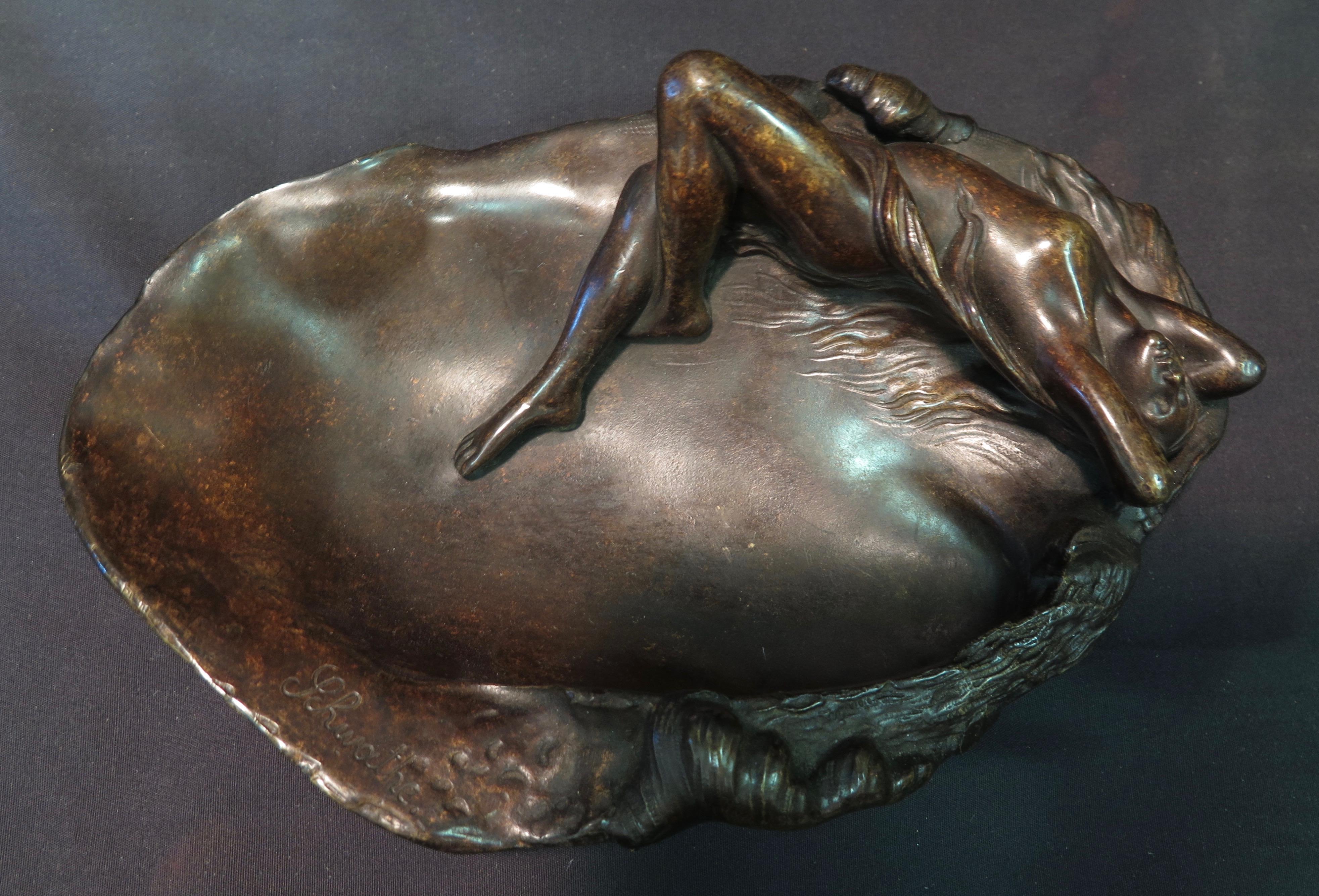 This early 20th century Art Nouveau period bronze vanity tray features a beautifully sculpted nude water nymph sunbathing along the water's edge. She is positioned in a seductive pose, seemingly raptured by the oncoming waves. The bronze, in dark