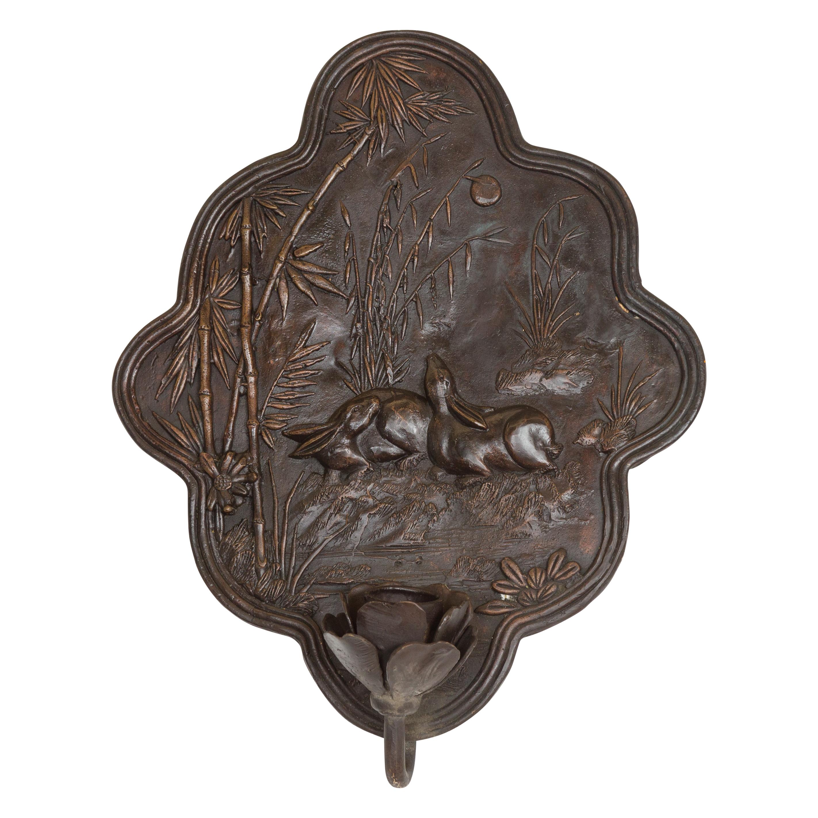 A vintage bronze candle sconce from the mid-20th century, depicting rabbits surrounded by bamboo. Created with the traditional technique of the lost-wax (à la cire perdue) that allows a great precision and finesse in the details, this wall sconce