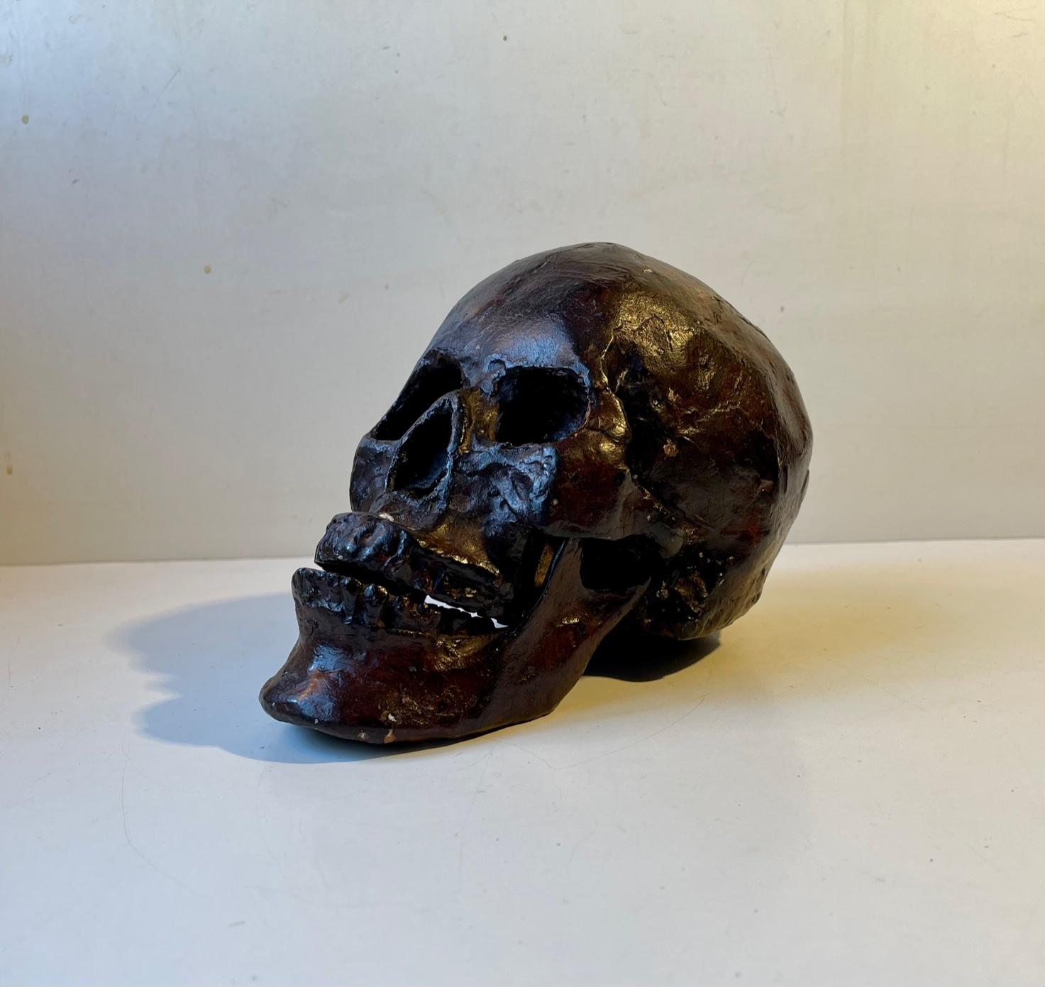 A rare 1:1 cast of a human skull in bronze. Its made from a cast of a real human skull, probably female, and is complete with teeth, lower- and upper jaw. This particular example has a brown verdigris patina. The skull as a symbol serves as a