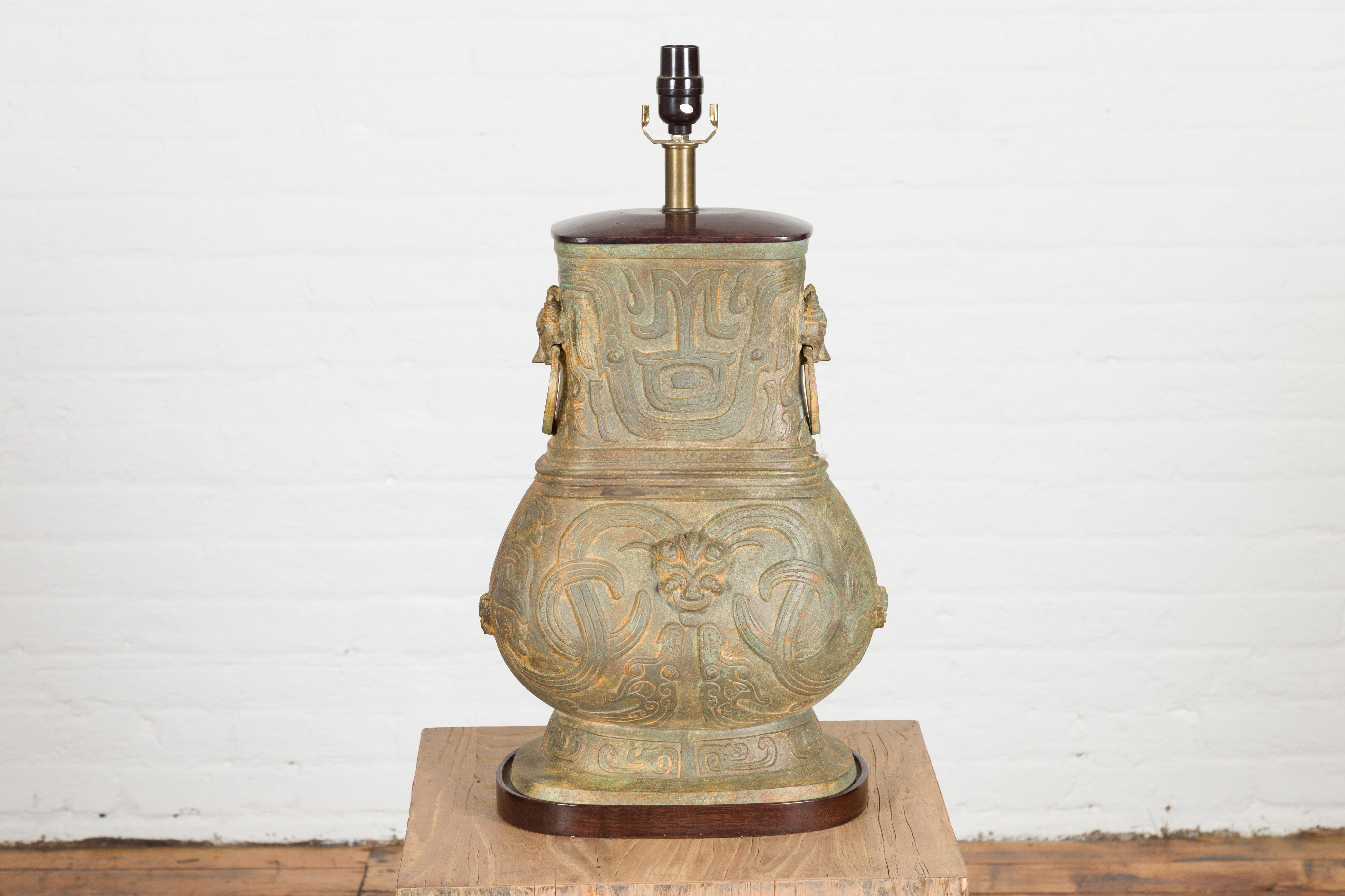 Lámpara de sobremesa china estilo vasija Hu de mediados del siglo XX, de bronce fundido vintage, con ondas entrelazadas, cabezas de dragón y animales míticos. Esta lámpara de sobremesa de bronce fundido presenta una silueta sinuosa con una parte