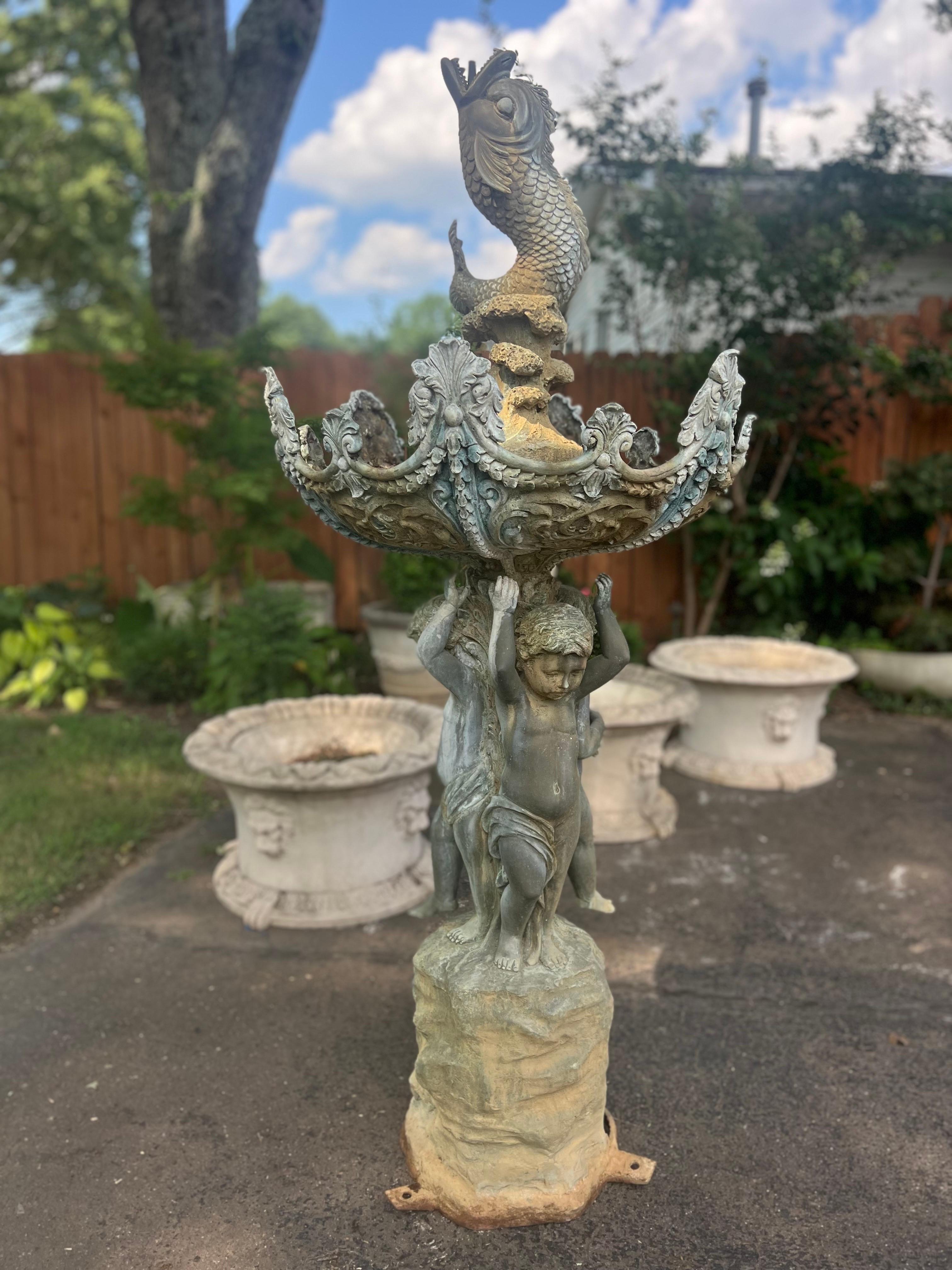 Vintage lost wax cast bronze Roman style fountain from the mid 20th century. 
Three Putti Cherubs holding fish.  Water comes from fishes mouth and drips to a bowl that then creates a waterfall over the three cherubs.  

Stands 72
