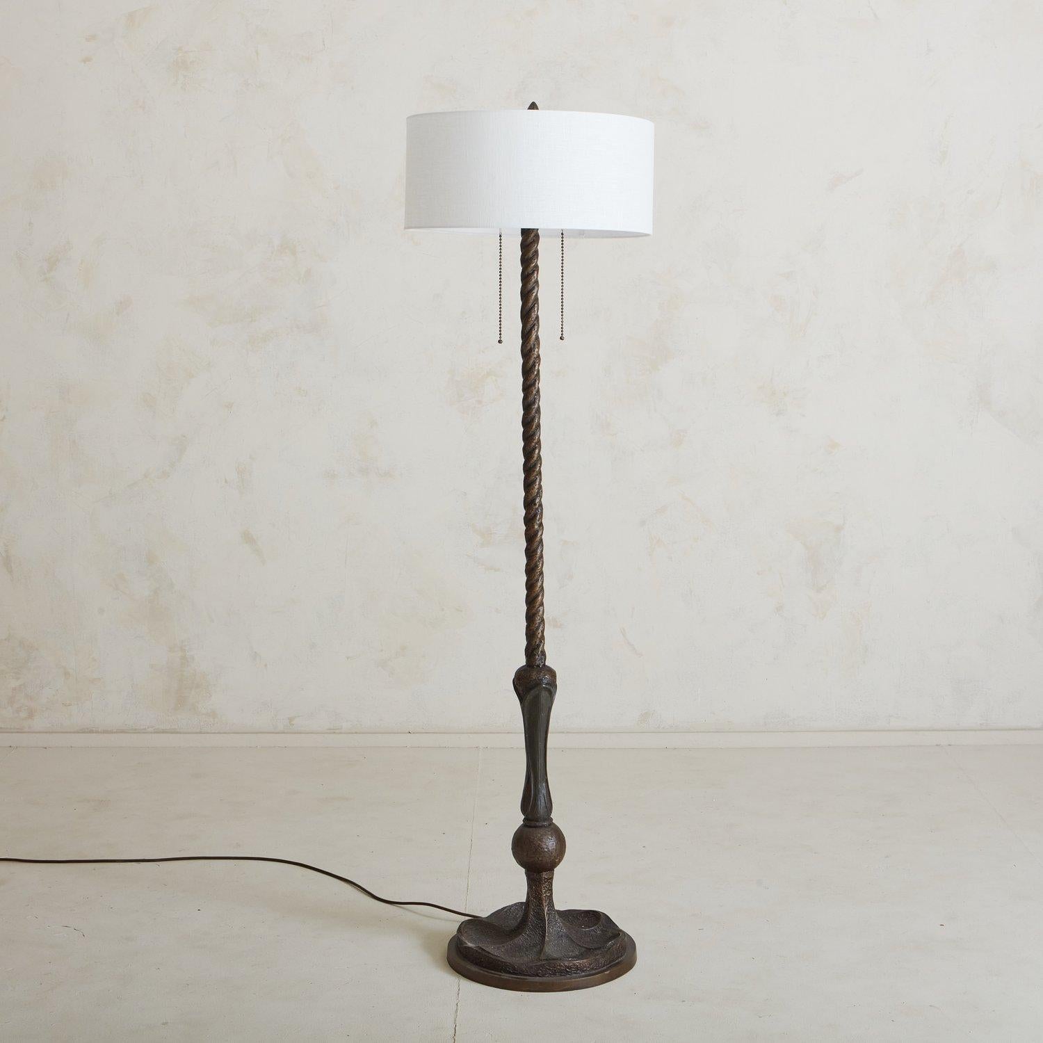 A 1960s bronze floor lamp featuring a circular base, braid motif frame and original, ornate gold tone finial. This piece would be the perfect accent to a favorite corner or reading nook. We love the subtle sculptural details on this beautiful German
