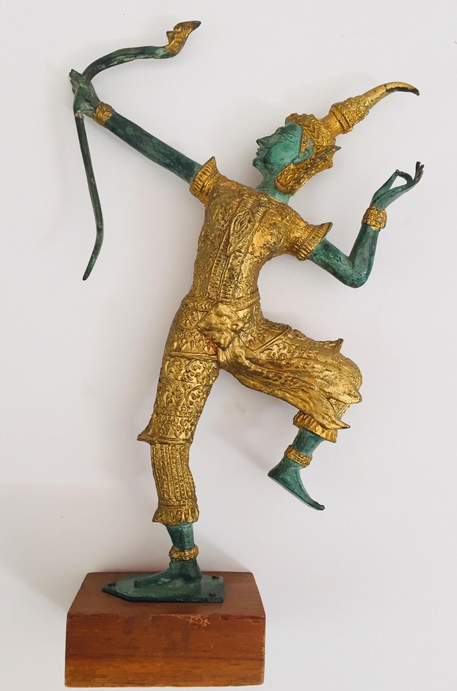 Vintage bronze statue in gold and green of Prince Rama shooting an arrow.
The Prince hero, Phra Rama (Rama), derived from Thailand’s national epic, Ramakien (Ramayana).
The figure is the distinguishing features of Khon, Thai classical drama.