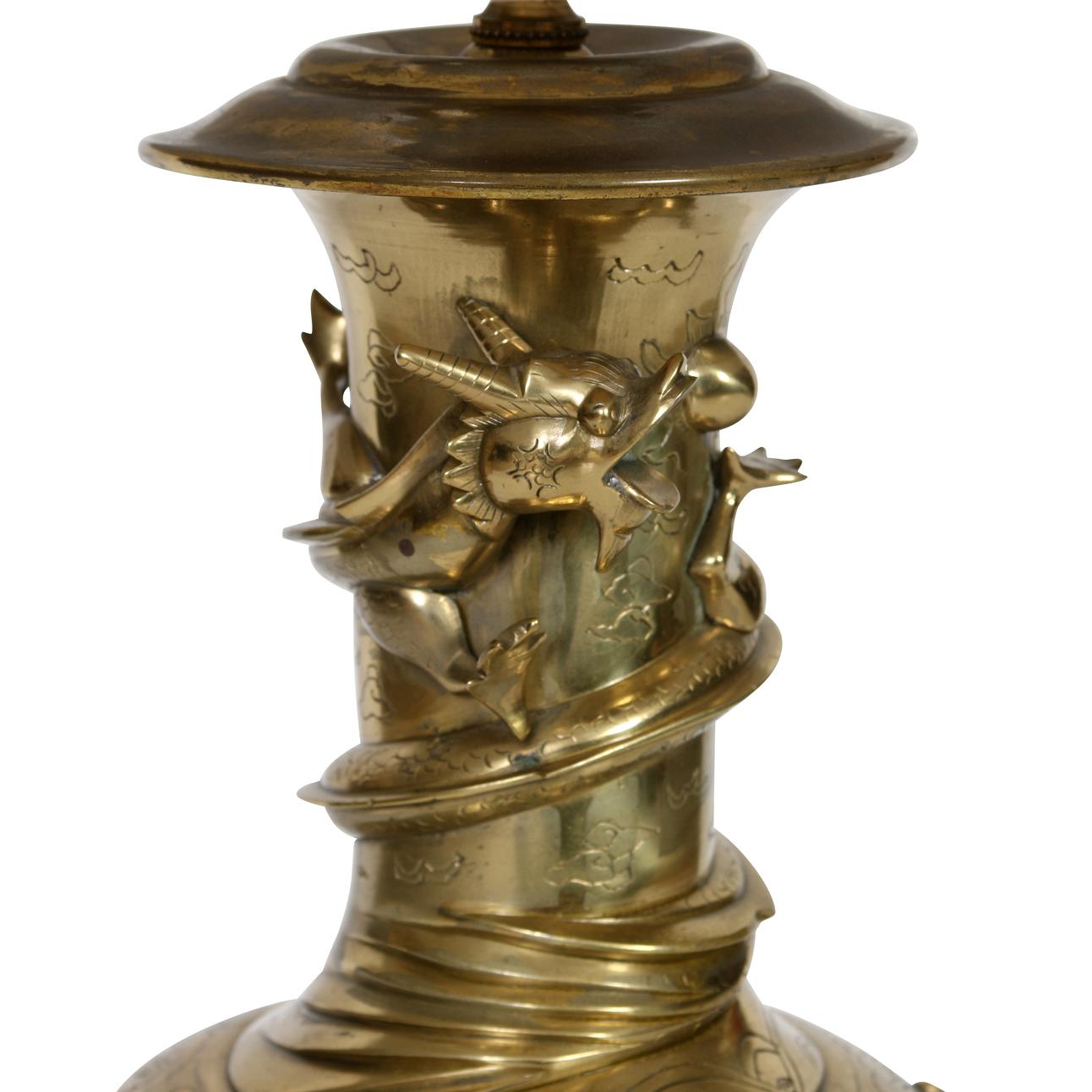 A vintage bronze table lamp wrapped with raised dragons in relief circling the lamp. The Asian style lamp sits on a round dark wood base. The shade is sold separately.
