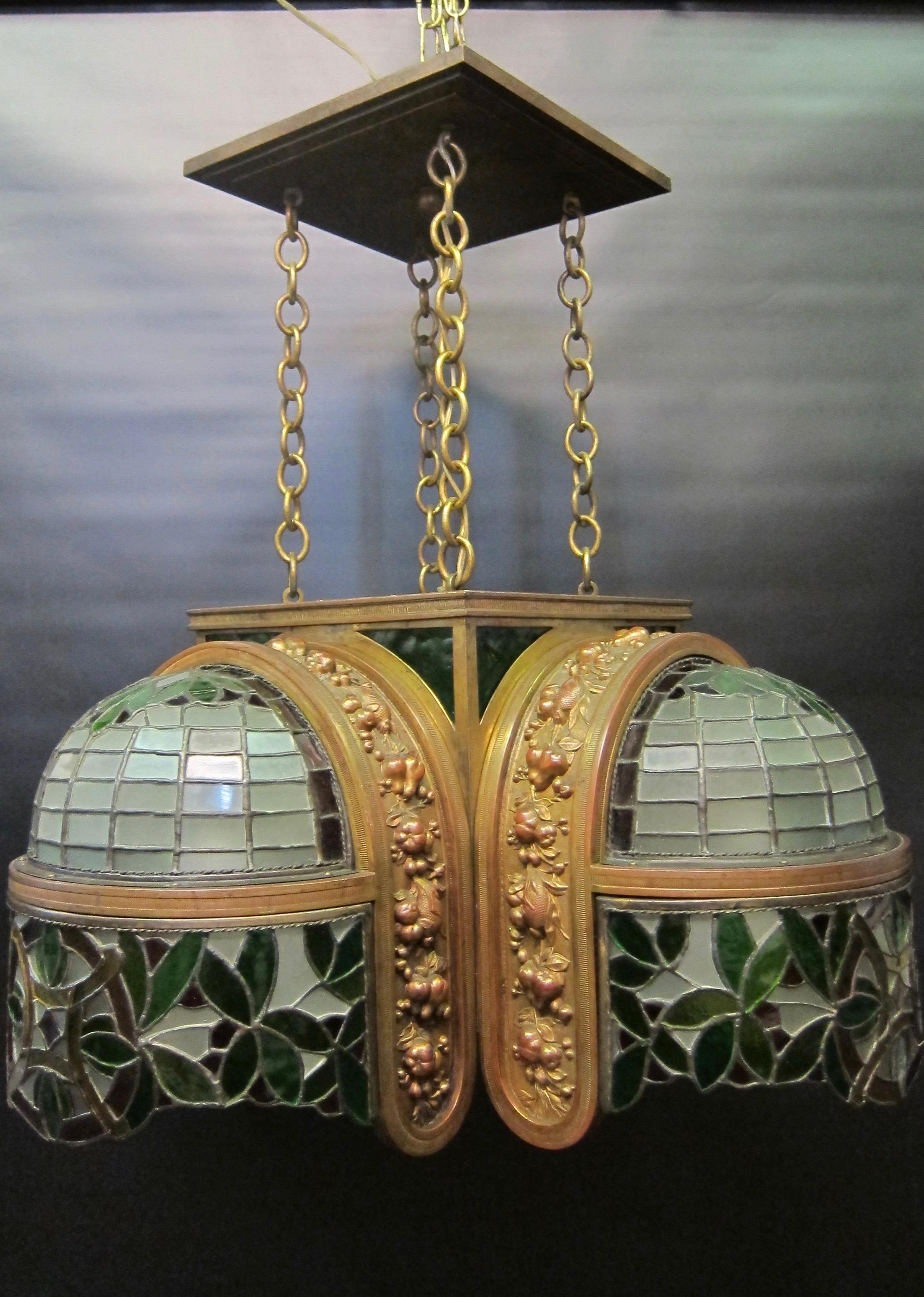 This unusual vintage 1920s French ceiling fixture is beautifully designed with four framed decorative bronze garlands draping over each of four extended glass canopies. These frosted leaded glass geometric canopies are embellished with aprons of