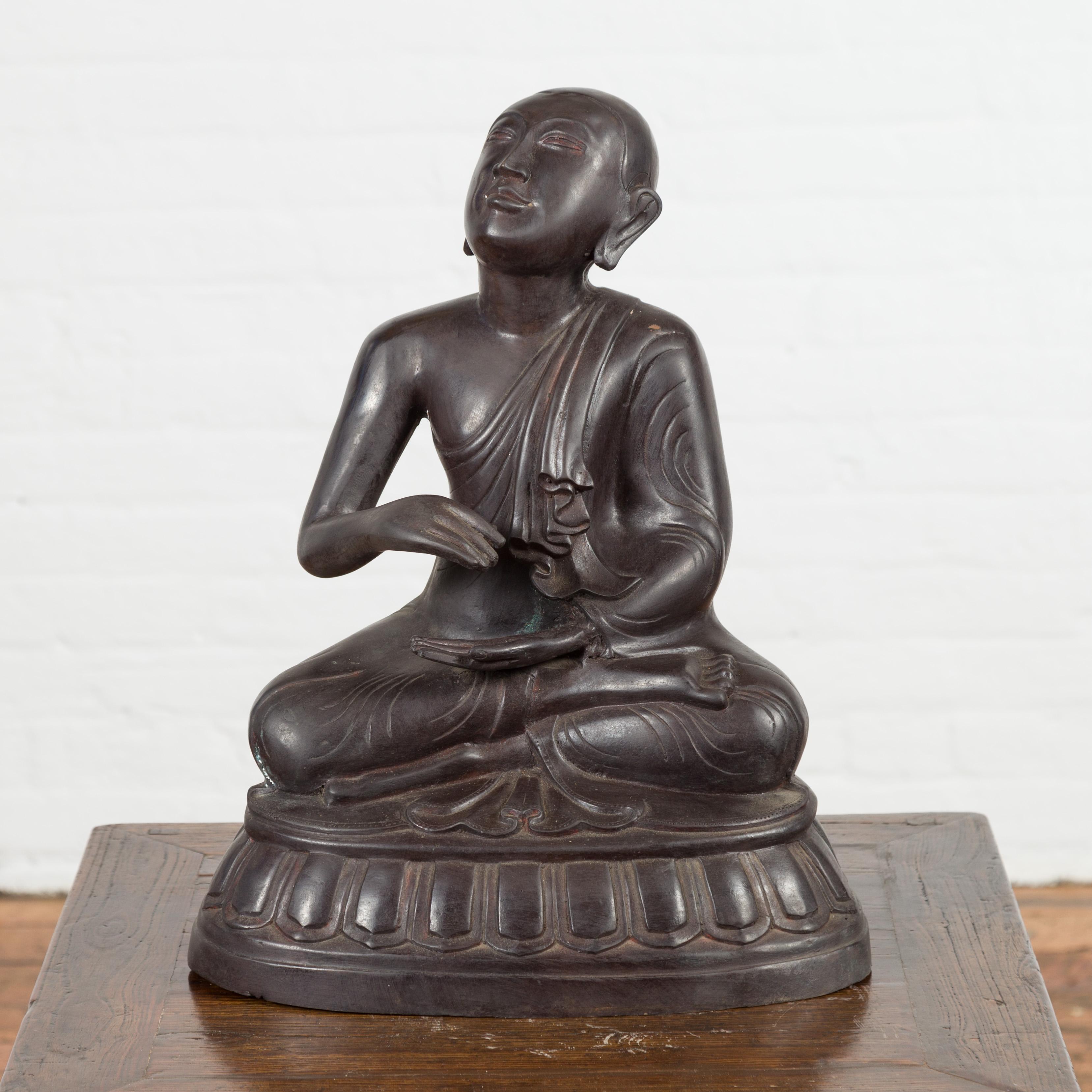 A vintage bronze sculpture depicting a praying monk sitting on a base. Created with the traditional technique of the lost-wax (à la cire perdue) that allows a great precision and finesse in the details, this vintage statue depicts a praying monk
