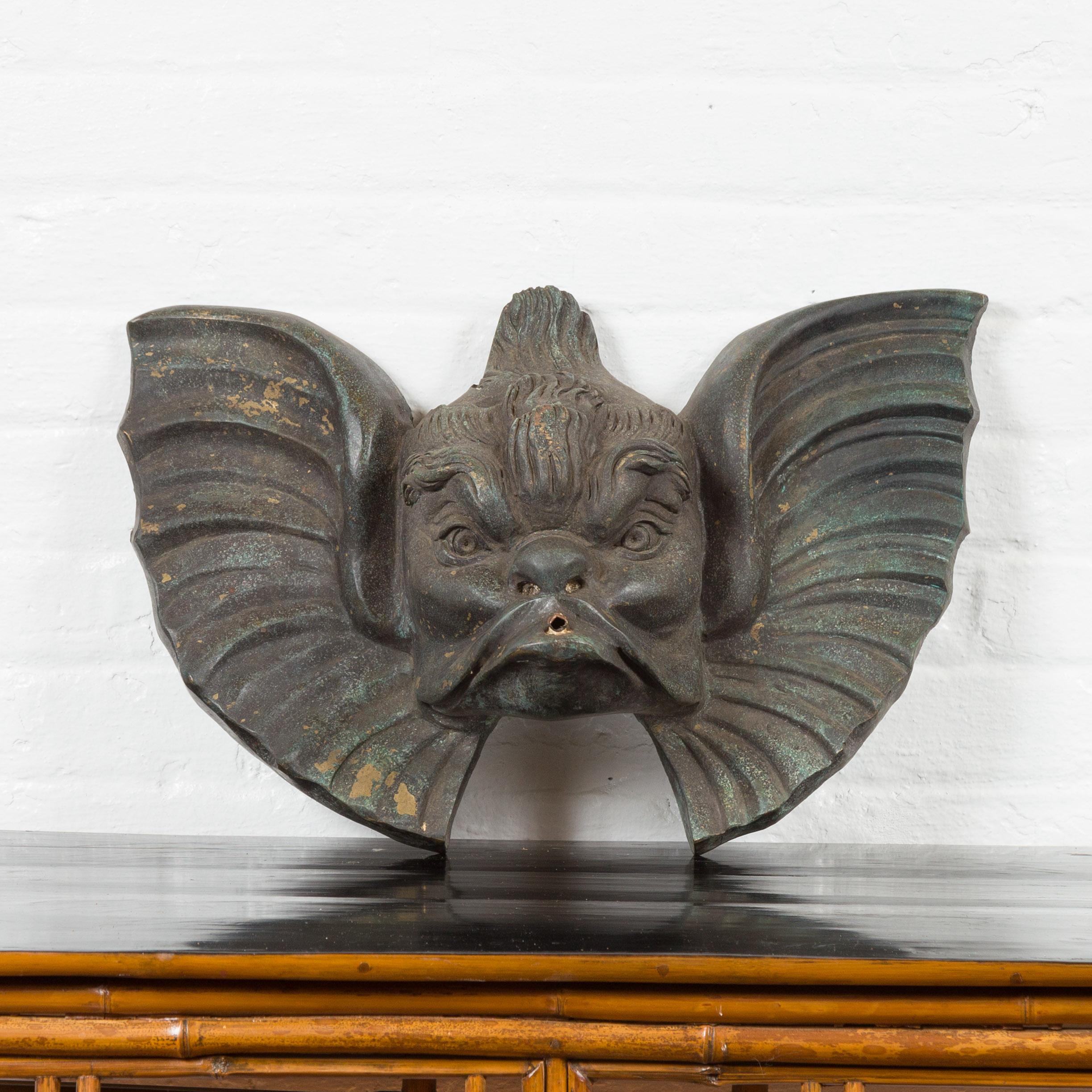 A vintage bronze mascaron inspired wall fountain from the mid-20th century with distressed finish. Created with the traditional technique of the lost-wax (à la cire perdue) that allows a great precision and finesse in the details, this bronze wall