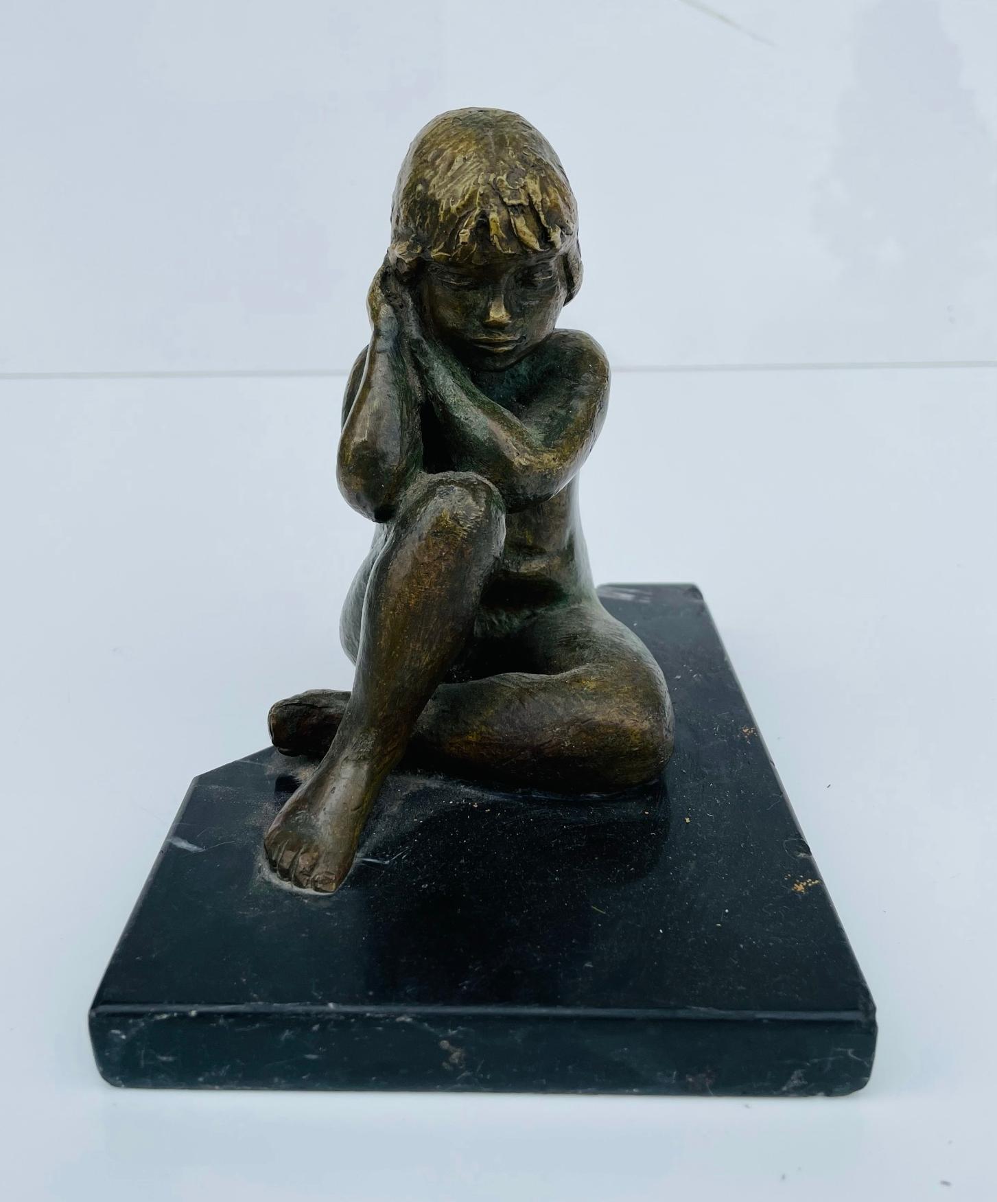 Introducing our exceptional Vintage Bronze of a Nude Girl Seating, Signed Chavez, circa 1960's – a timeless piece of art that exudes elegance and charm. This exquisite statue captures the beauty of a young girl, delicately seated atop a sleek black