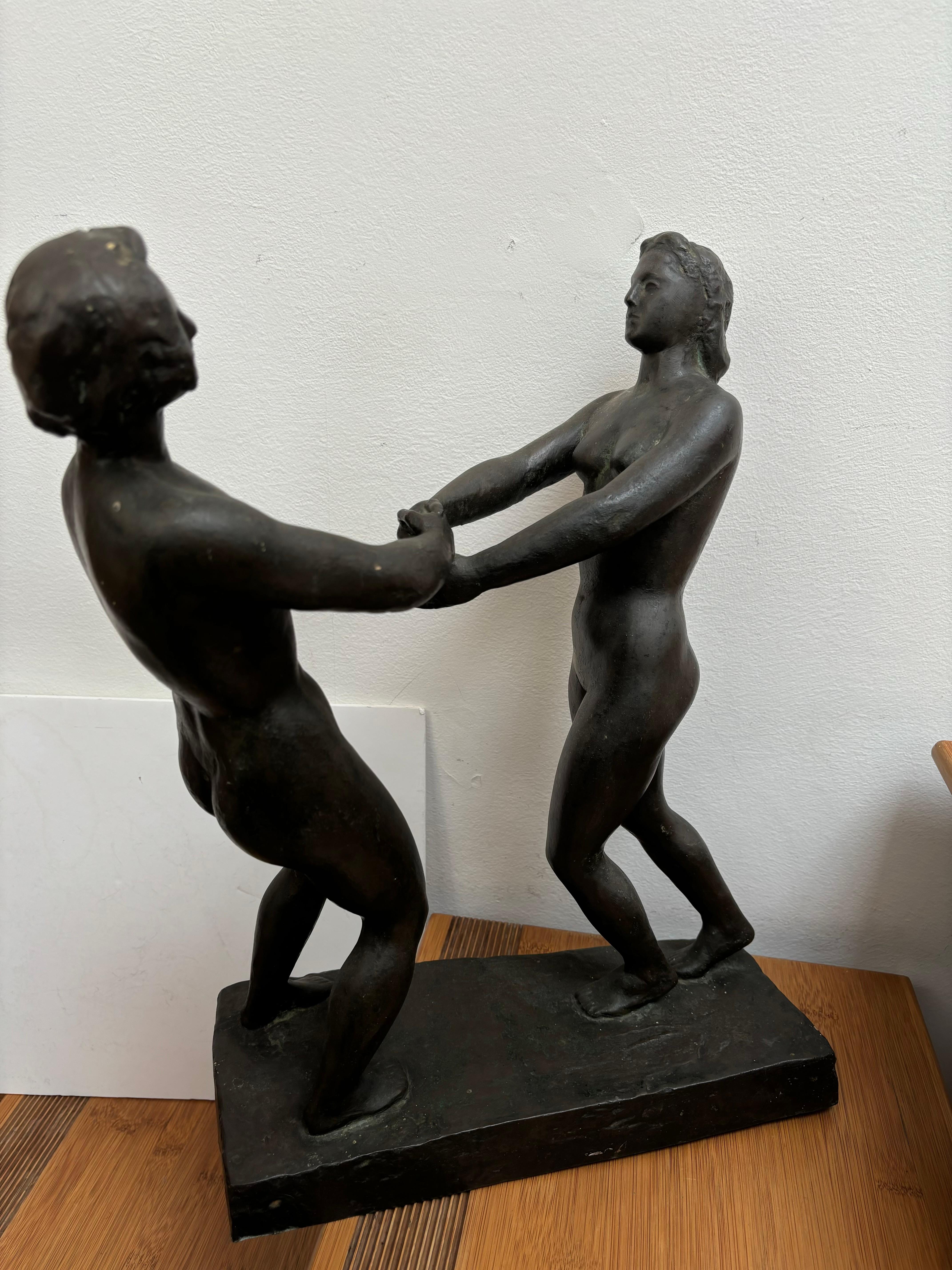 Scultura in bronzo molto imponente che raffigura due figure femminili che si tengono per mano, probabilmente danzando. Sono raffigurati in stile antico, come ad esempio Venere. Queste figure poggiano su una base di bronzo. 
La base è firmata