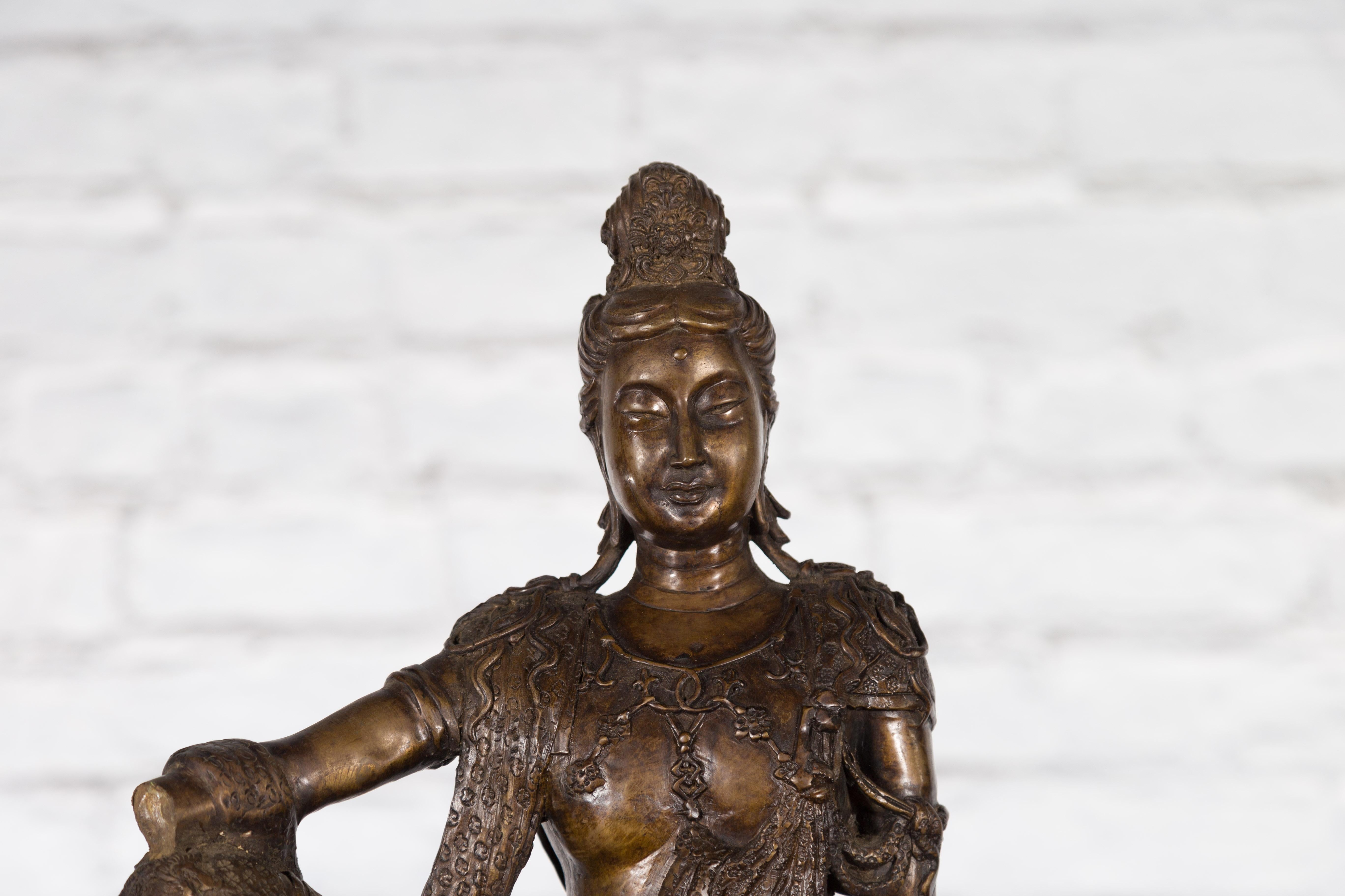 Bronze Statuette vintage représentant Quan Yin assis sur une formation rocheuse en vente