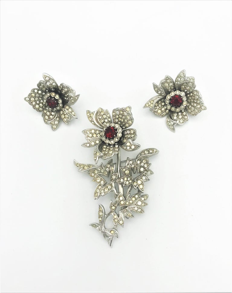 An early set, brooch and ear clip from the 1940s USA unsigned. Flower and leaves are all set with small rhinestones. In the bloom a cut red rhinestone. During this time the flower was very popular as a tramplr, so the flower is mobile! The same