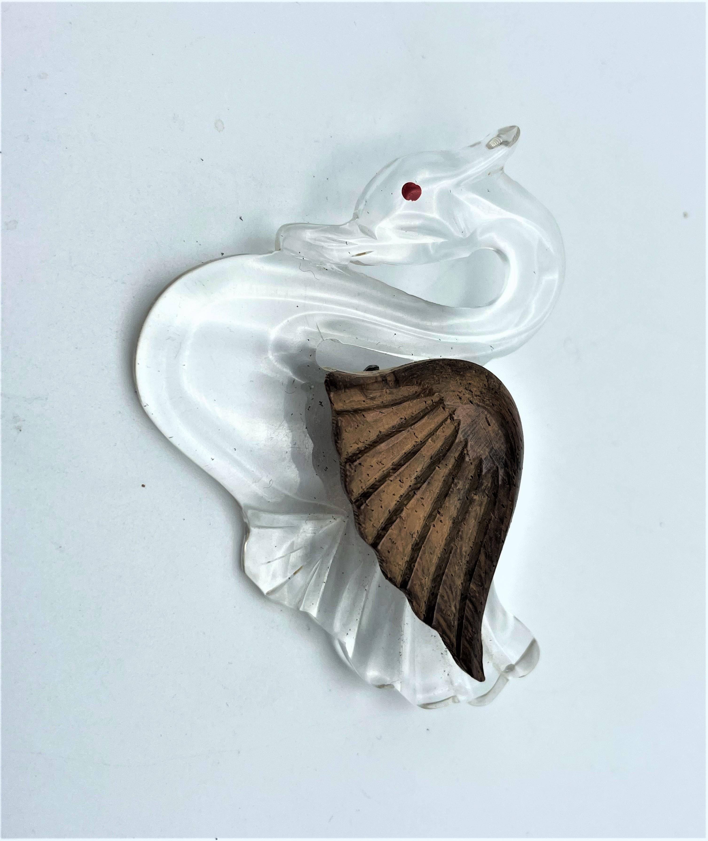 Cleary wonderful  brooch in the shape of a swan made of clear Lucite/Acrylic. The brown swings are made of carved wood.  Window glass/acrylic from the aircraft was used for this type of jewelry in the 1940s USA. Non was marked by a