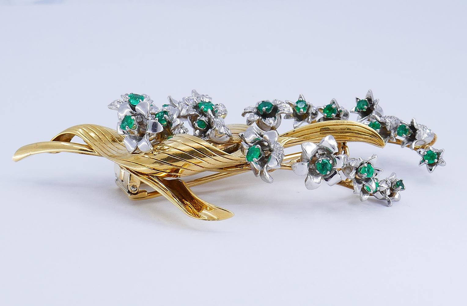 A gorgeous vintage 14 karat gold lily of the valley brooch, featuring emerald and diamond.
The vintage brooch has a floral design. The flowers are meticulously crafted of platinum. Their petals are accented with diamonds and the centers with