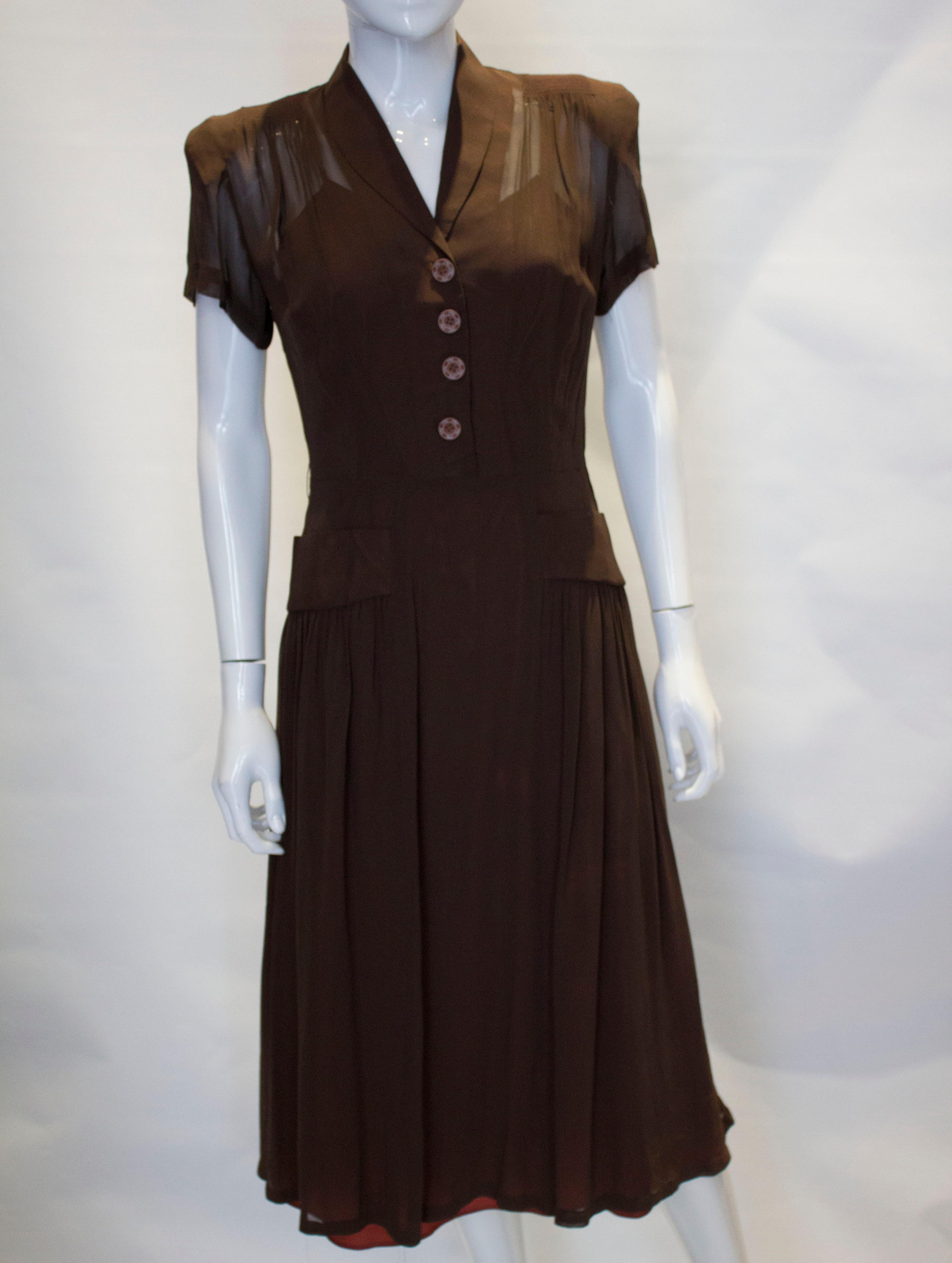 A pretty dress from the 1940s. The dress has a shawl collar, side zip opening, gathering at the shoulders and two pockets at waist level.
