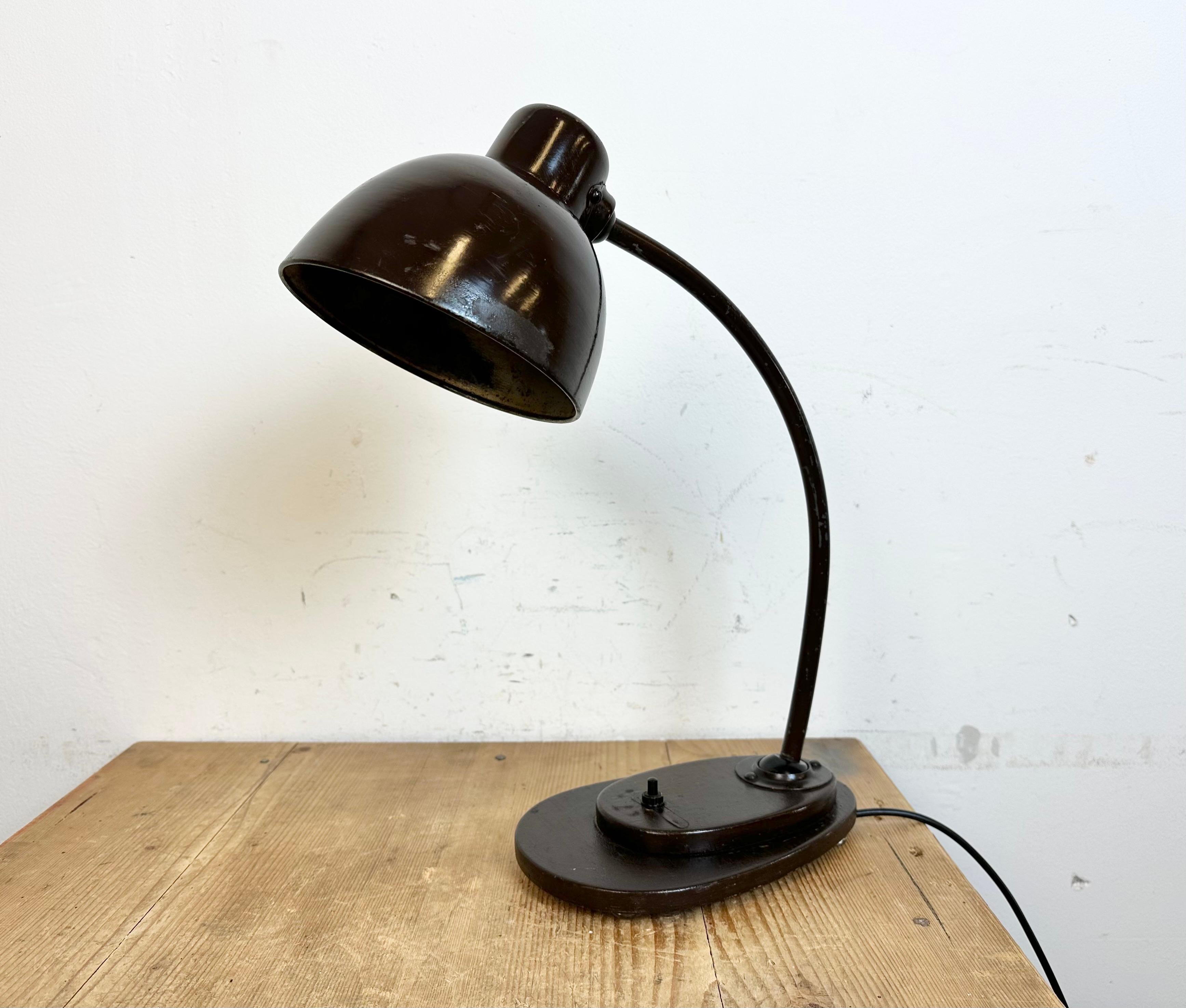 This dark brown  industrial desk lamp was made in former Czechoslovakia during the 1960s. The lamp has an aluminium shade, a wooden base and iron arm with two adjustable joints. Original bakelite socket requires standard E 27/ E26lightbulbs. New