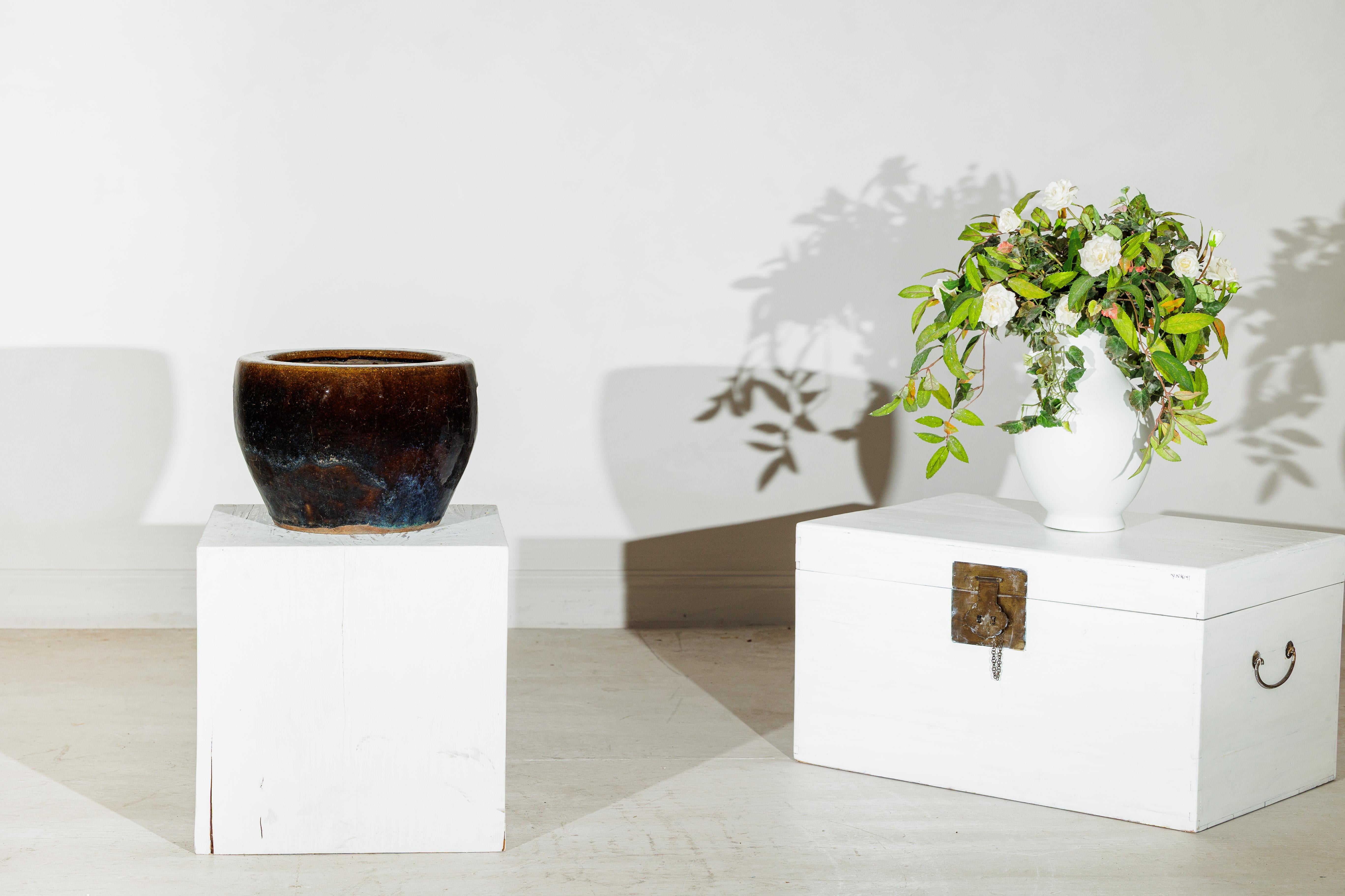 Questa fioriera cinese vintage è caratterizzata da un profondo smalto applicato a mano che passa da un caldo marrone screziato sul bordo a un concentrato di blu e nero verso la base. Il vaso è realizzato a ruota con un labbro spesso e arrotondato e