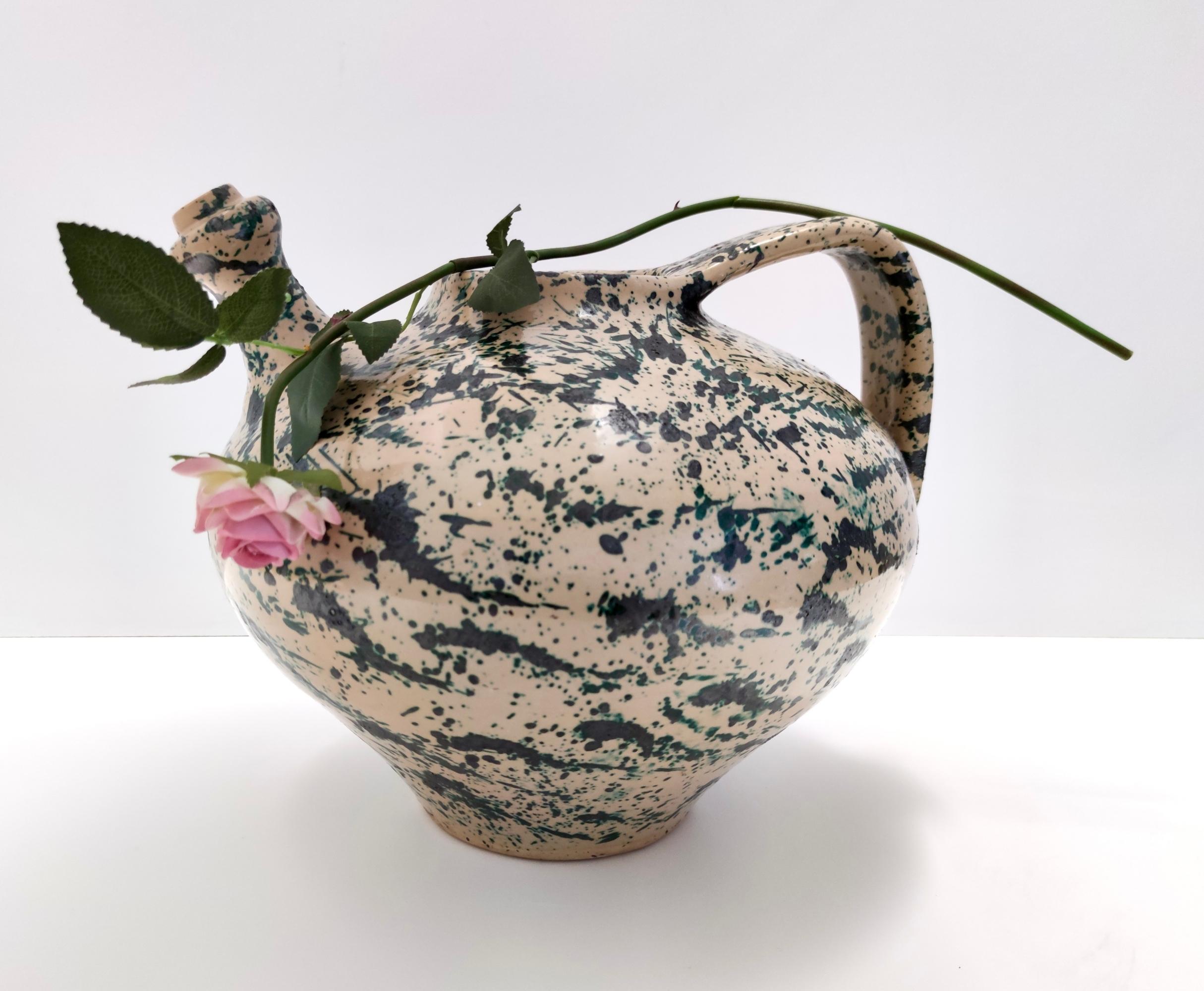 Fabriqué en Italie, années 1950. 
Ce vase est réalisé en terre cuite laquée et peinte à la main avec une décoration similaire à l'action painting et une forme qui rappelle l'outre étrusque en terre cuite, mais qui, pour l'anse et la base plus fine,