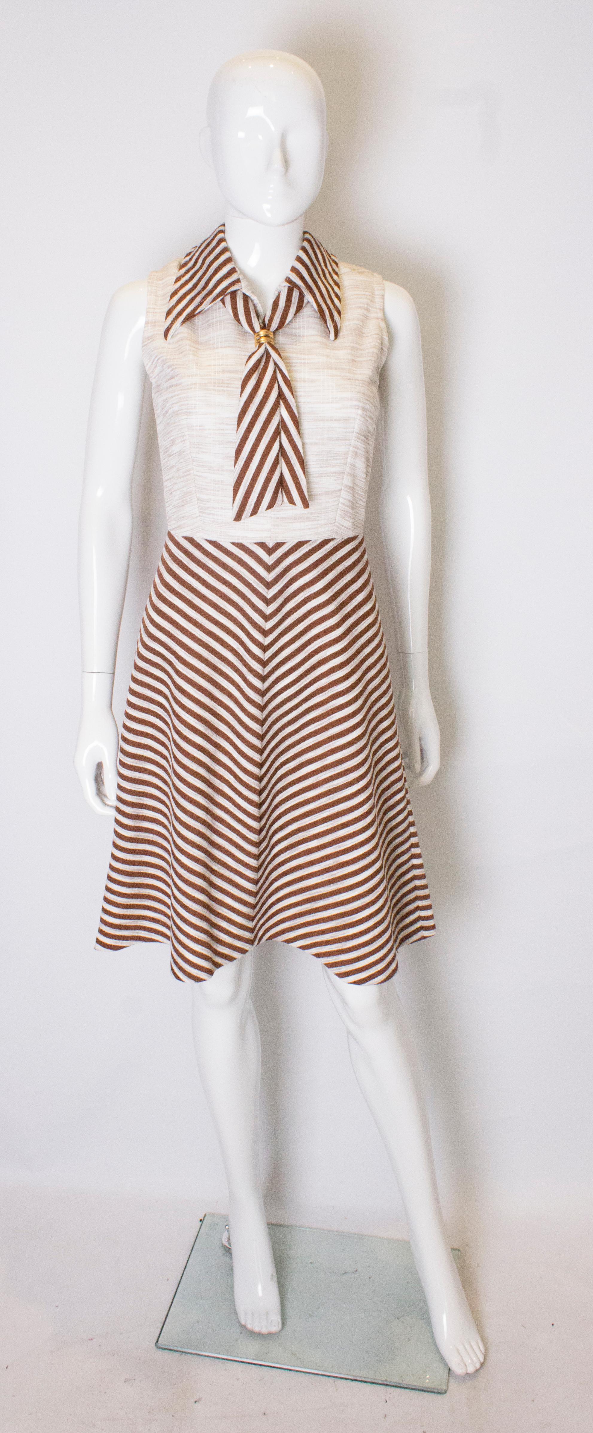 A chic and easy to wear day dress in a brown and white stripe. The dress has a brown and white skirt , collar and tie with a central back zip.