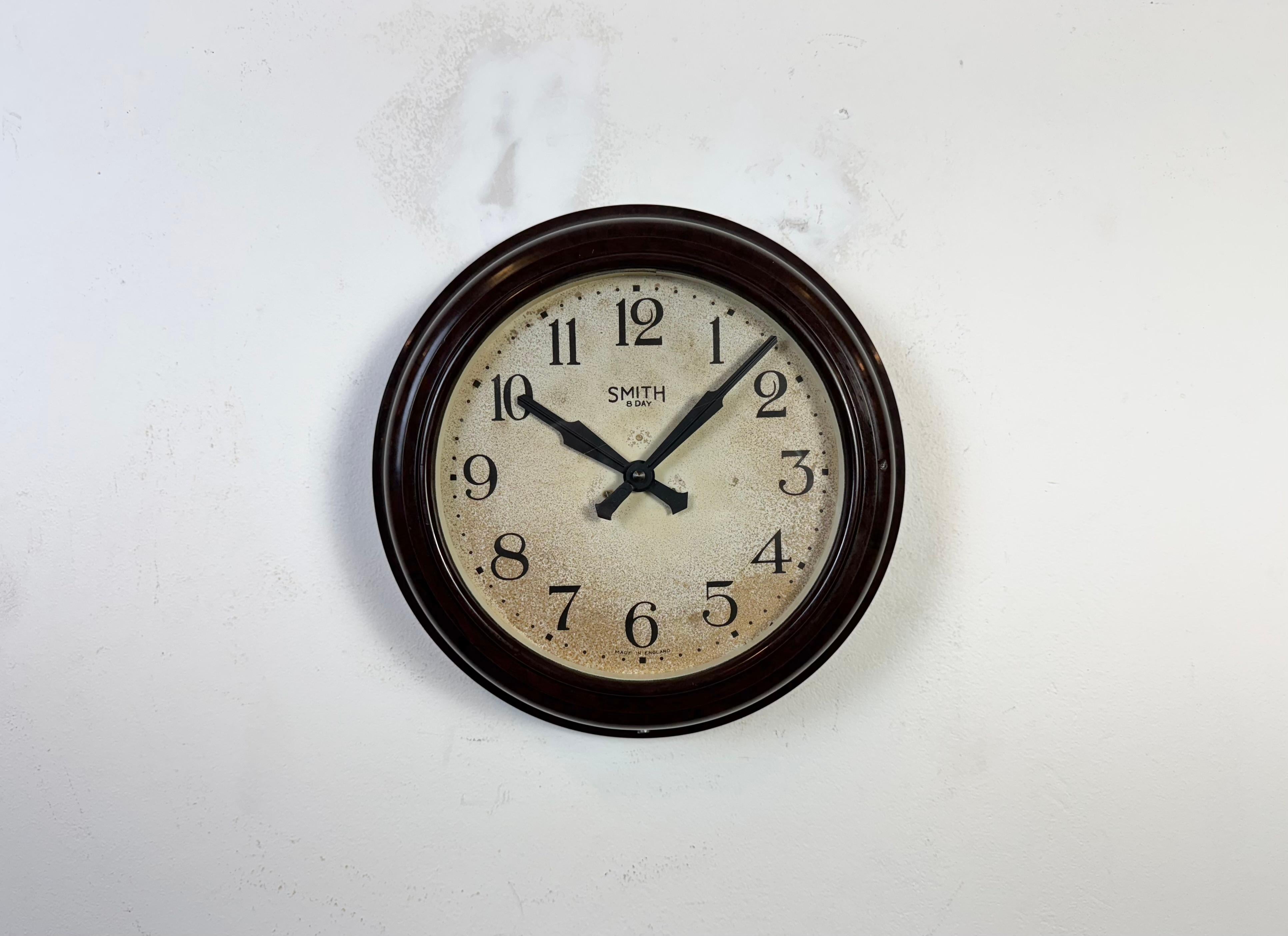 Cette horloge murale a été produite par Smith en Angleterre dans les années 1950. Elle présente un cadre en bakélite brune, un cadran en fer, des aiguilles en aluminium et un couvercle en verre transparent. La pièce a été convertie en un mécanisme