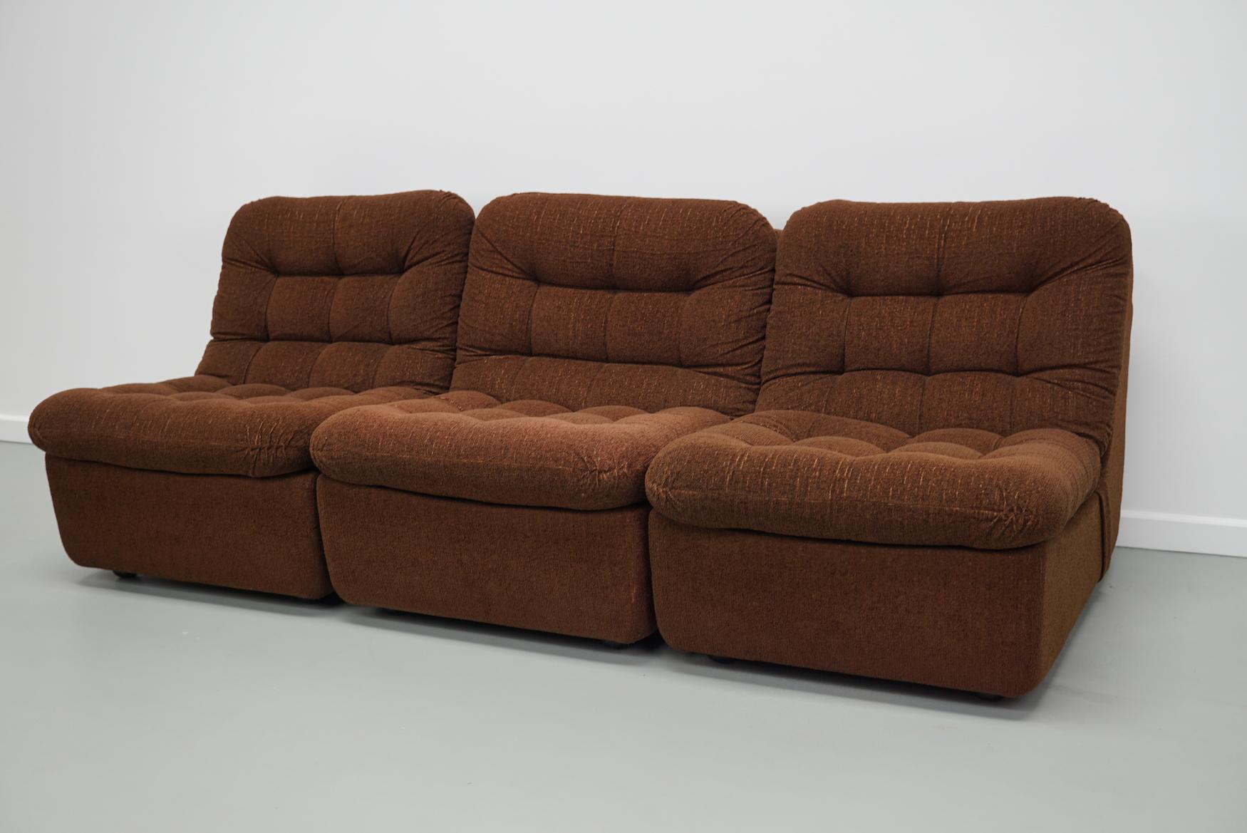 Questo divano modulare vintage è stato realizzato intorno agli anni '70 in Germania. Presenta 3 elementi rivestiti in tessuto boucle marrone. È molto comodo e presenta solo minimi segni di usura, come mostrato nelle foto, e rimane in buone