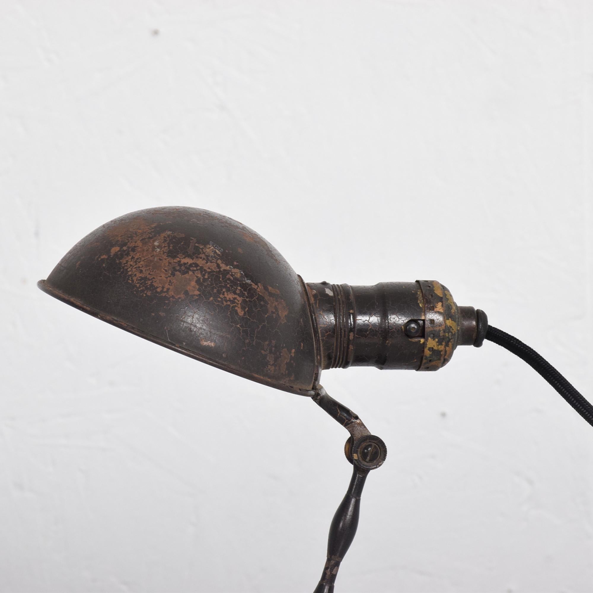 Unique Industrial table lamp that can be adjusted into multiple positions. Painted metal. Color brown.

Lamp can be hung on the wall as a wall sconce original unrestored finish with vintage patina. Wear consistent with age and use. Minor fading.
