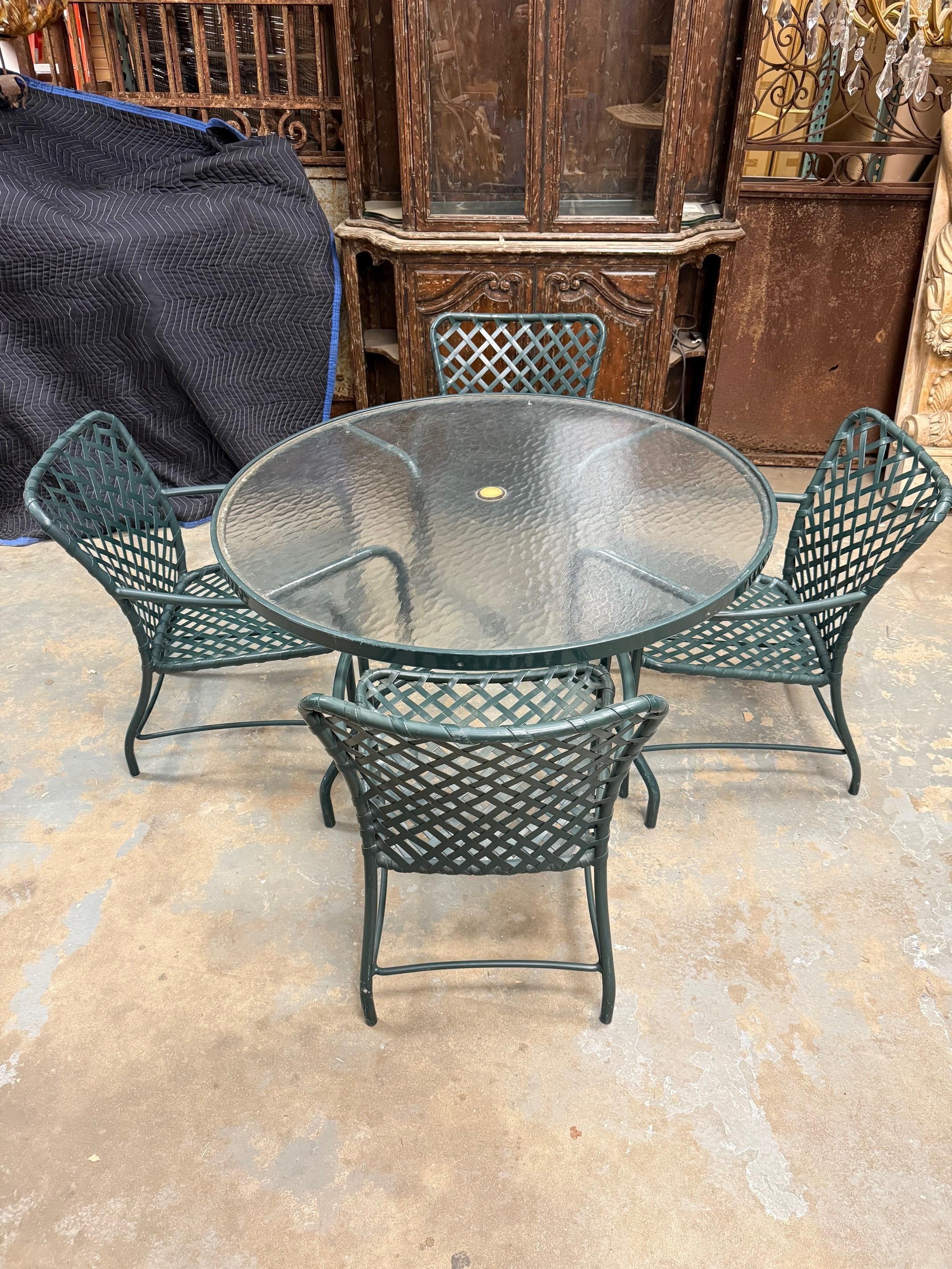 Vintage Brown Jordan Tamiami Collection five piece outdoor dining set which includes a table and four armchairs. The armchairs have green aluminum frames with green straps all in very good condition. The table is 48