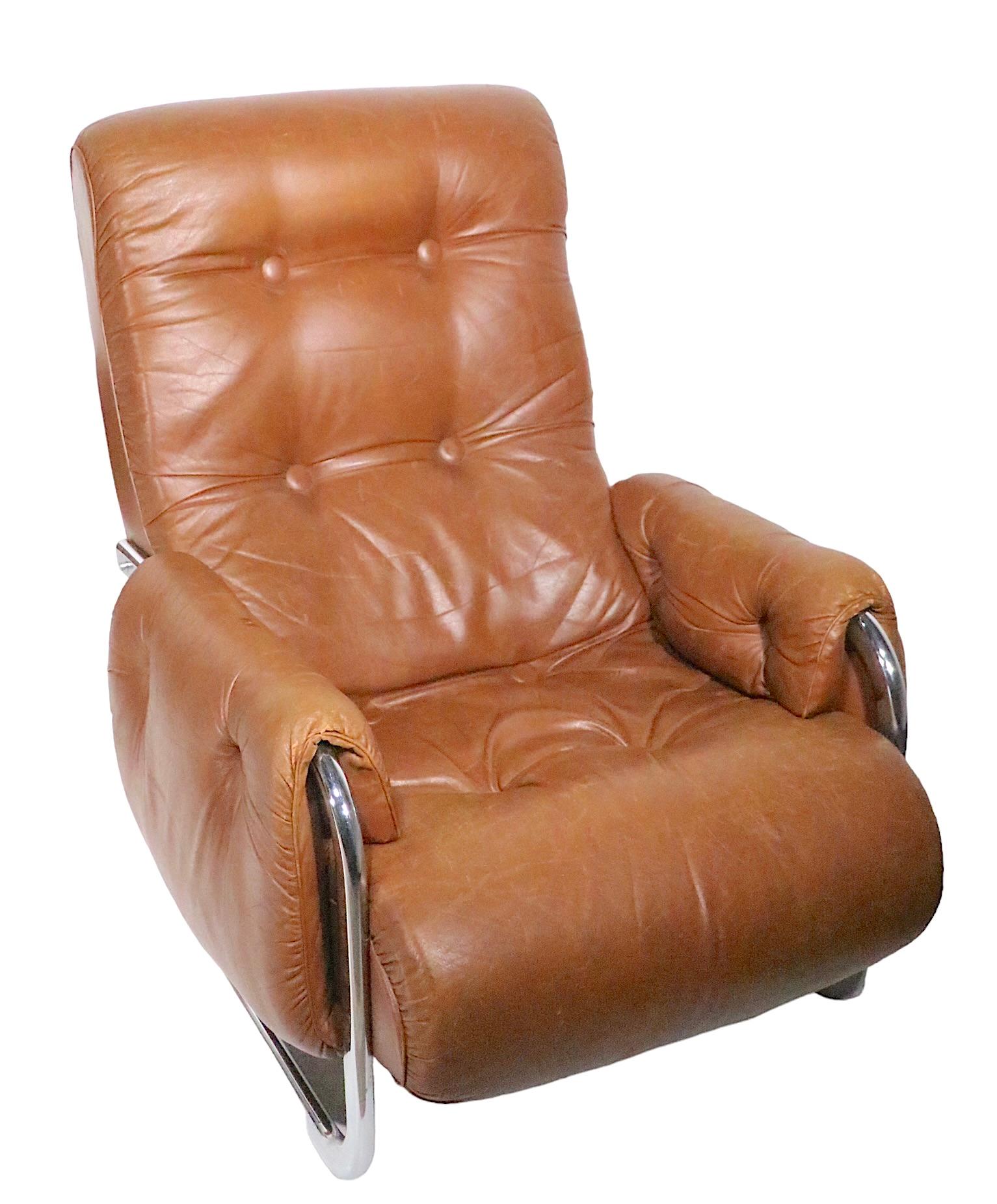 Chic Post Modern low lounge chair and ottoman, in brown baseball mitt leather, with a bright chrome frame. The chair and ottoman have cantilevered bases, adding to the architectural style of the design. This example is in good, original, ready to