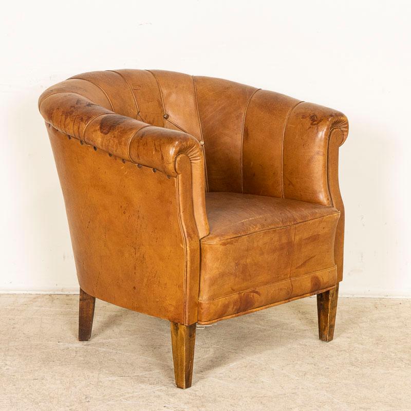 Vintage leather club chairs are sought after these days by those seeking to add an aged element to a modern home. This handsome barrel chair will do just that with a rich patina that only comes from years of use, all accented with self piping. The