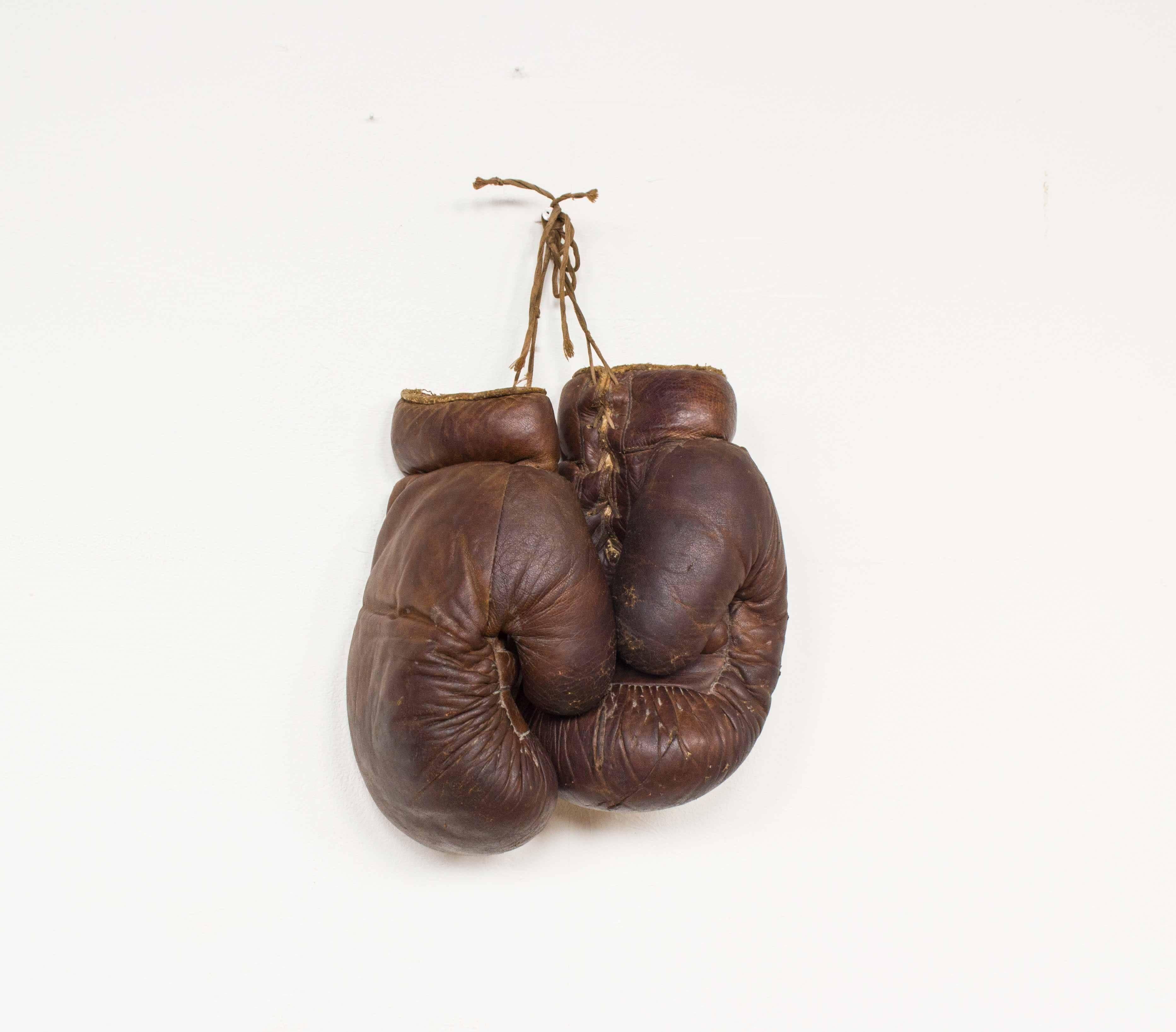 Pair of small, leather boxing gloves. Dating from the 1940s-1950s. There are many user traces such as scratches and cracks in the leather.