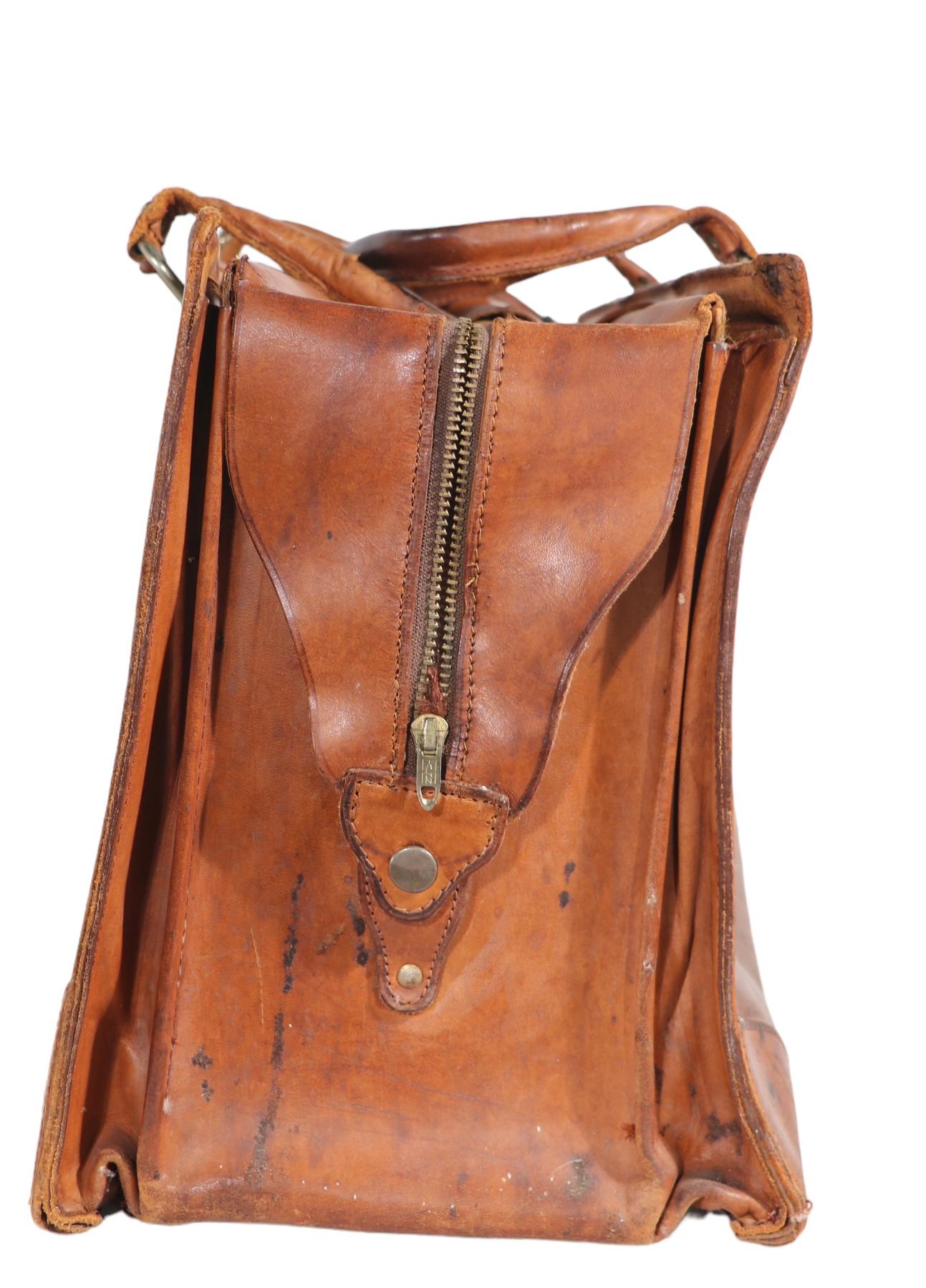 Great vintage hand bag, small suitcase, or document bag etc. The bag features three compartments, two small side pockets, and the main center space, which  can be zipped closed. The handles have a velcro closure, and padded leather grip, the top can