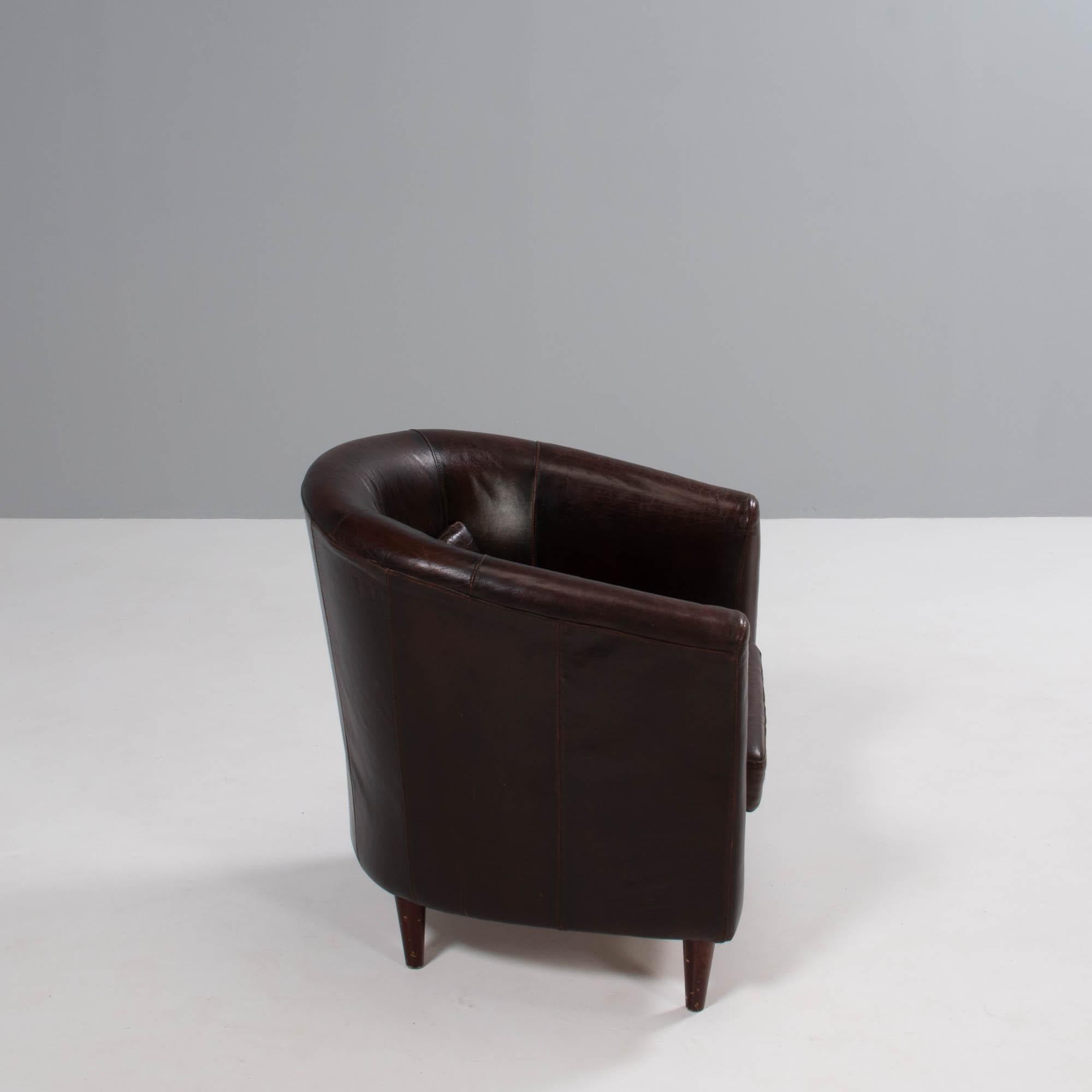 A pair of vintage tub chairs, fully upholstered in dark brown leather with wooden feet.

The chairs have curved backrests and integrated arms, creating the tub silhouette with a seat cushion and additional back cushion for extra comfort.

A