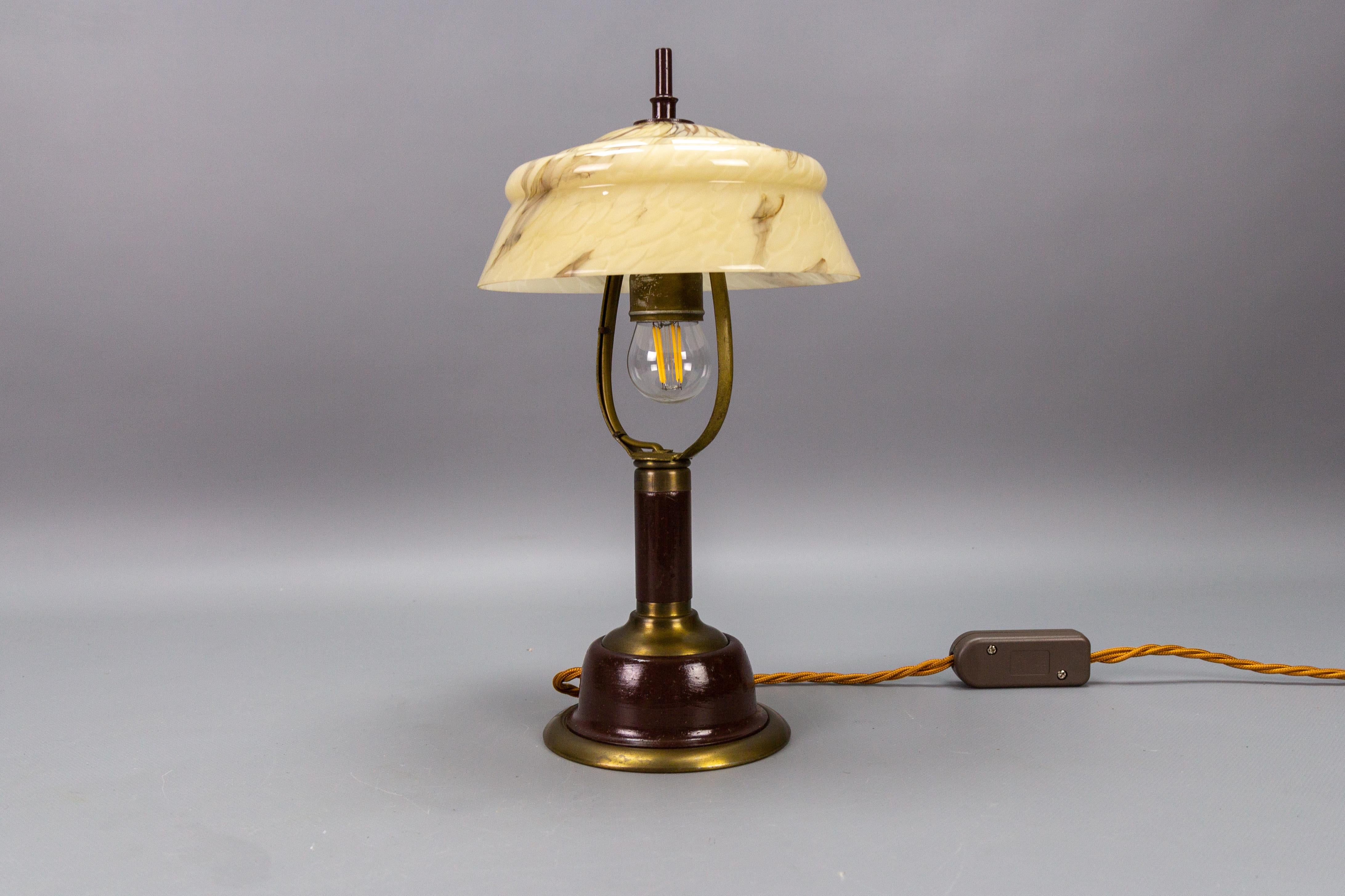 Lampe de table réglable vintage en verre marbré et métal, Allemagne, circa 1950.
Cette charmante lampe de table ou de bureau de style Art déco présente un corps en métal de couleur marron et laiton avec un abat-jour en verre marbré - l'abat-jour en