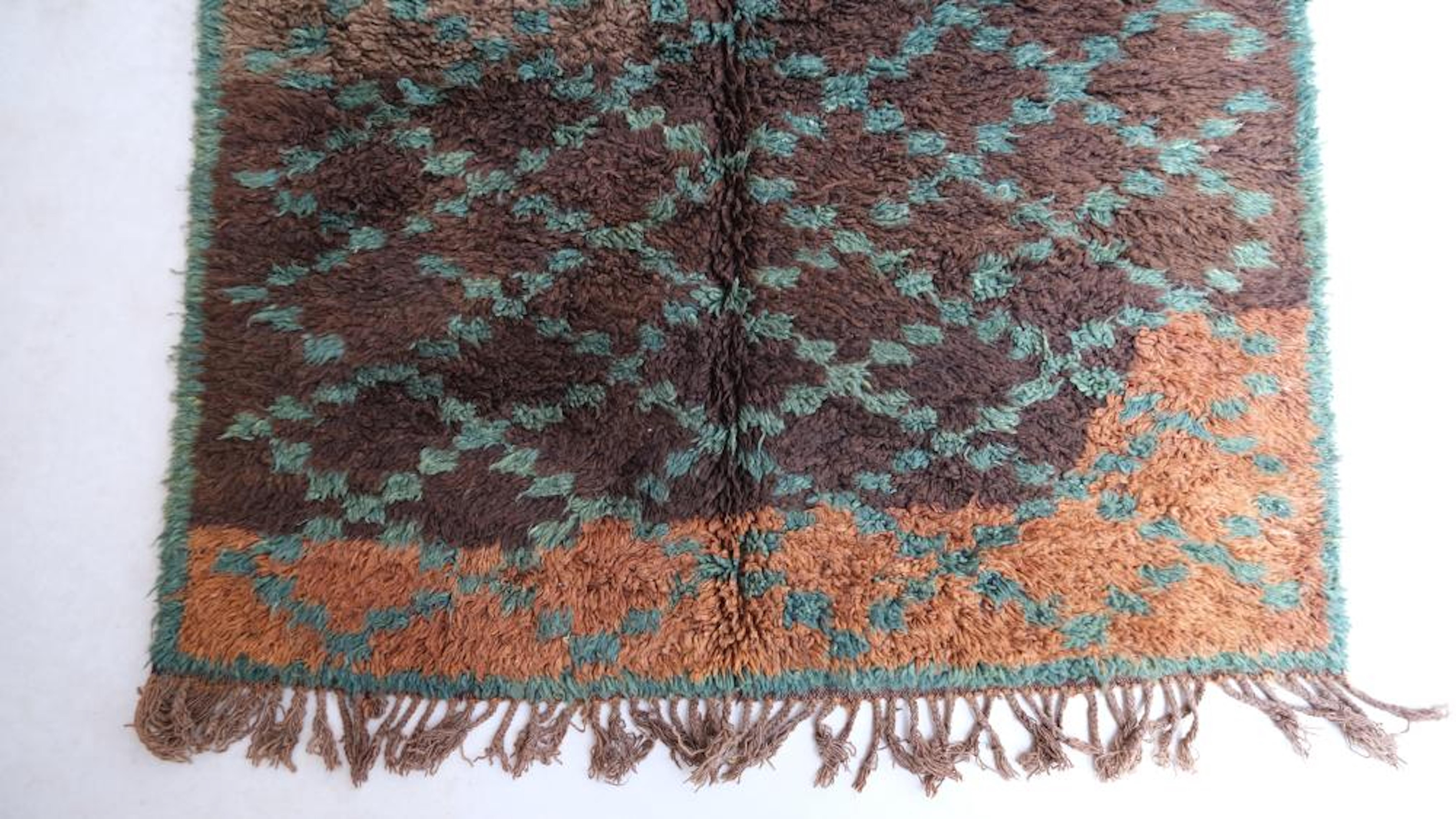 Una alfombra marroquí vintage increíblemente especial de la tribu Beni M'Guild. Esta alfombra o pasillo neutro de color chocolate cálido presenta un color desigual único con un dibujo cruzado azul verdoso turquesa en contraste. El fondo marrón