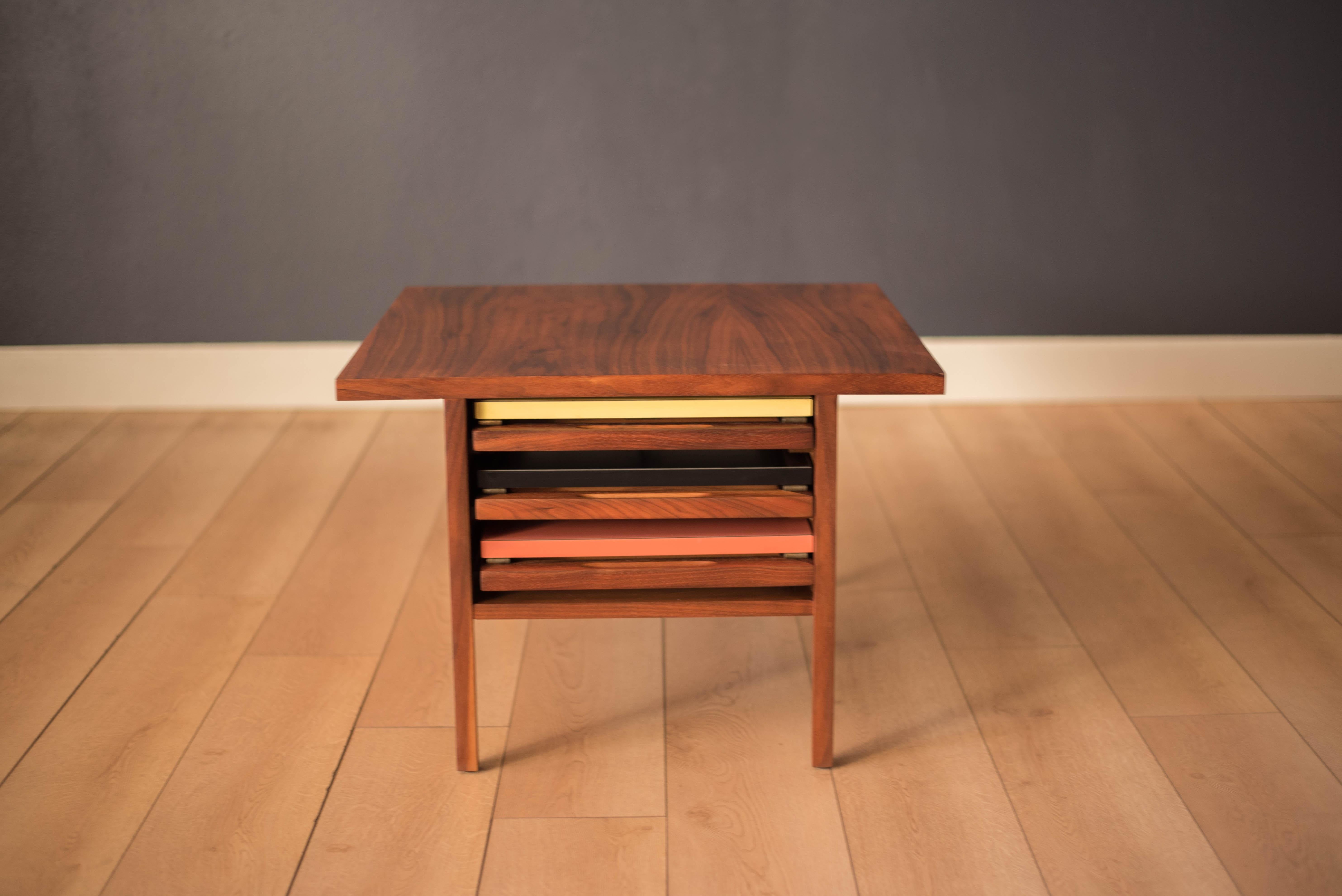 Mid Century walnut coffee table and nesting side tables designed by John Keal for Brown Saltman. This unique piece includes three foldable tray tables that store inside cabinet. Tables have collapsible solid walnut legs, brass supports and