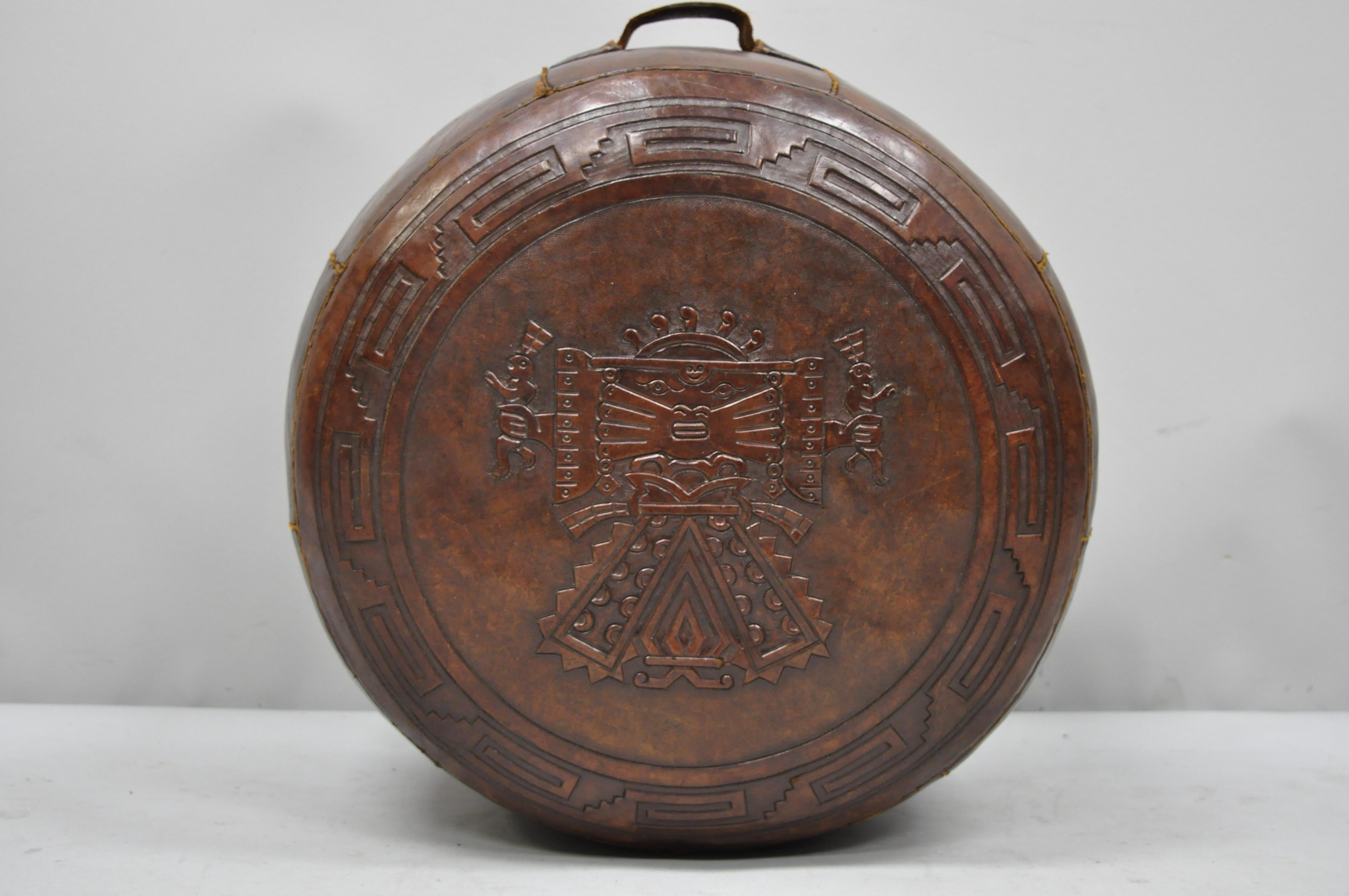 Vintage Brown Tooled Saddle Leather Peruvian Ottoman Hassock with Handle. Item features embossed figure to center, thick high quality saddle leather, single handle, wonderful age patina. Circa mid 20th Century. Measurements: 12