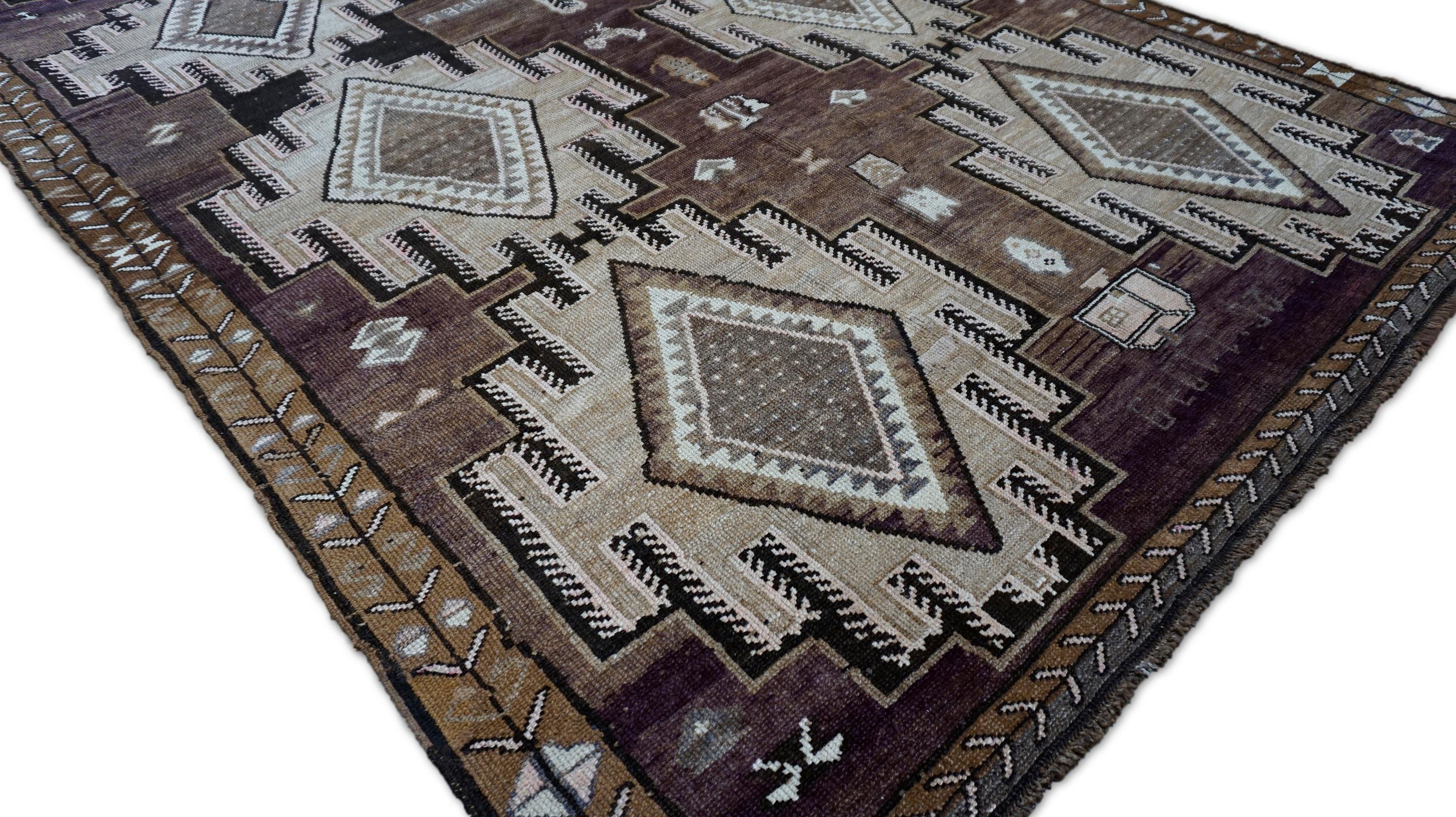 This striking hand-knotted wool rug presents a bold tribal aesthetic infused with deep, earthy tones and symbolic design elements. Rug features a powerful central medallion motif surrounded by stepped geometric forms, rendered in a rich palette of