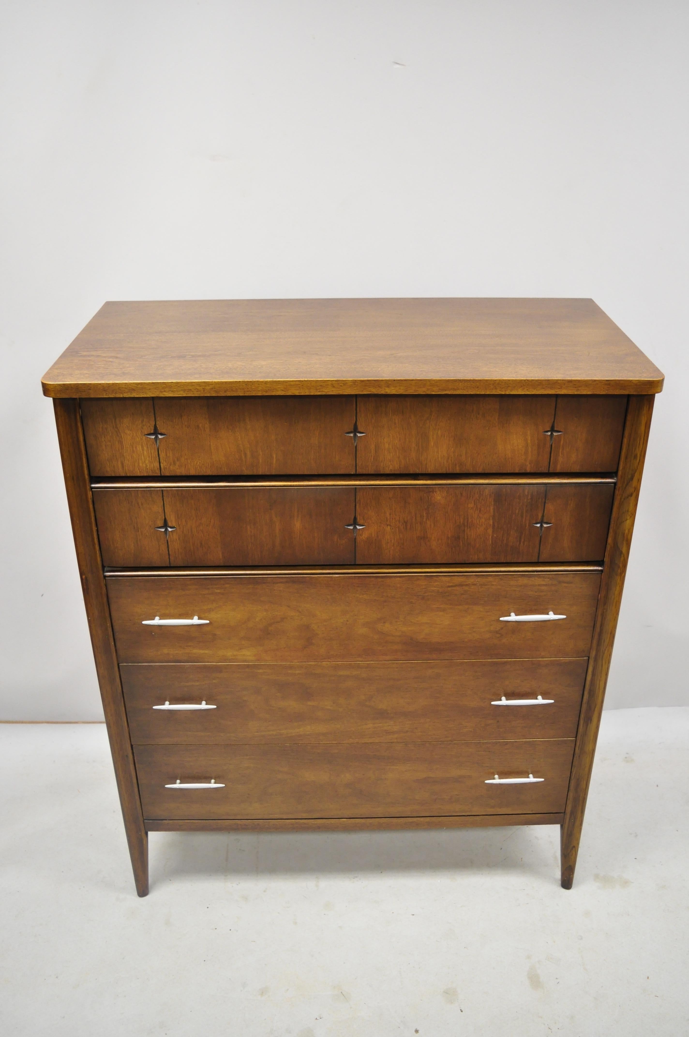 Vintage Broyhill Saga Mid-Century Modern walnut carved star tall chest dresser. Item includes carved star drawer fronts, beautiful wood grain, 5 dovetailed drawers, tapered legs, sleek sculptural form, circa mid-20th century. Measurements: 46.5