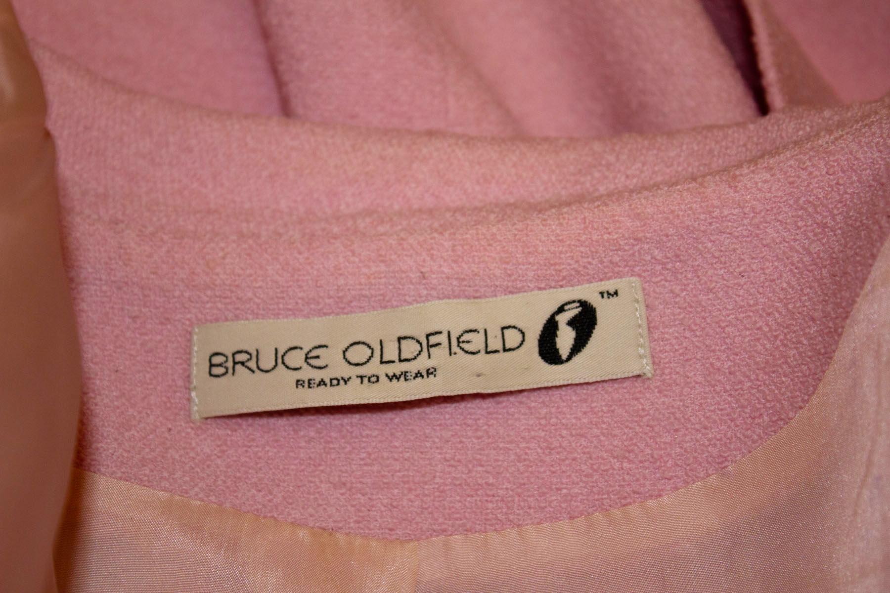 A charming vintage pink boucle coat dress , by Bruce Oldfield - dress make to the Queen.  The coat dress has great tailoring, with a double breasted front  and small gatherings at hip leval . The coat dress is fully lined.
Size UK 14, measurements