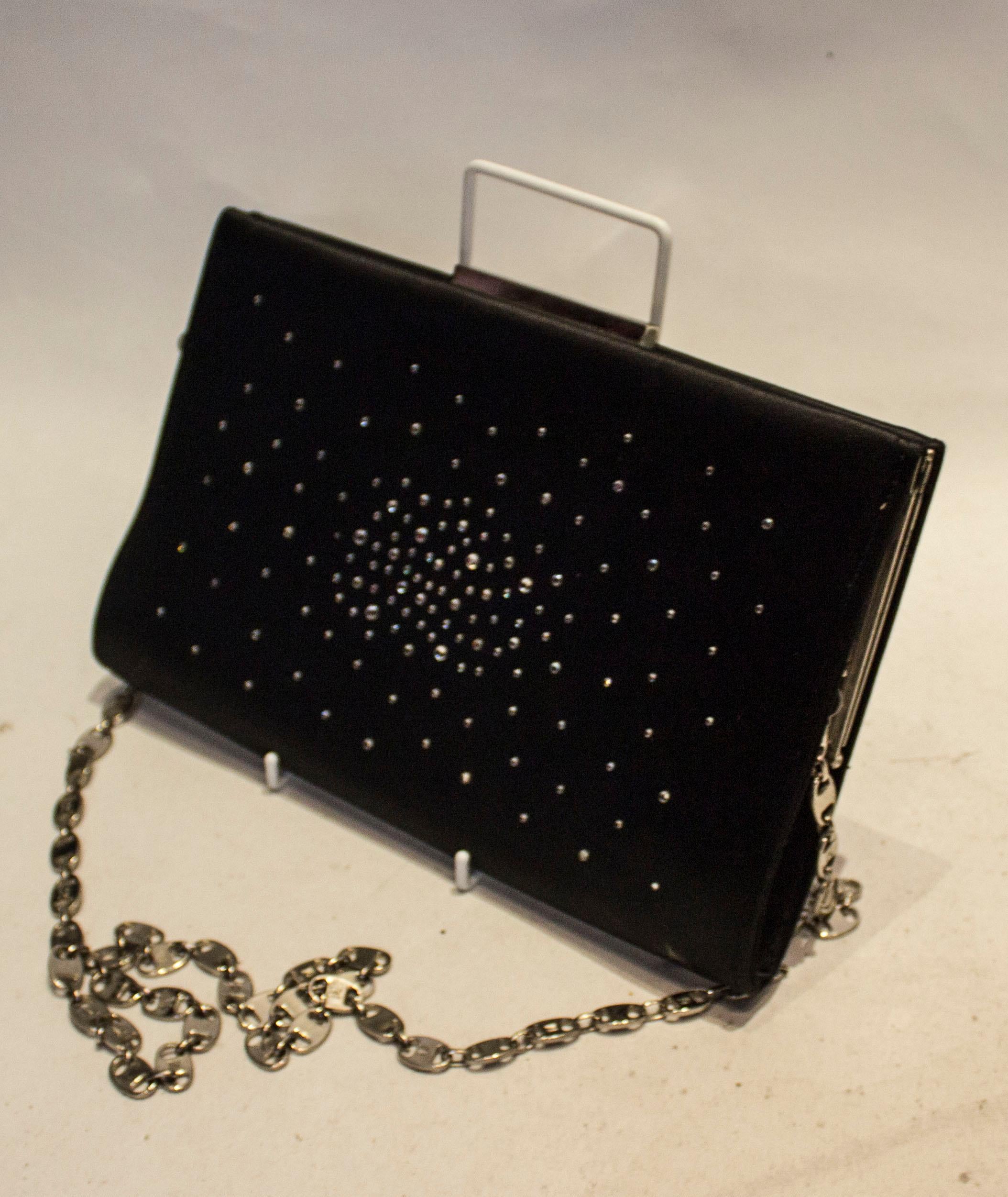 Eine schicke Vintage-Abendtasche von Brun Magli Couture. Die Tasche aus schwarzem Satin, beidseitig mit Diamanten besetzt, hat eine Innentasche und eine Öffnung oben.

Abmessungen: Breite 10 1/2'', Höhe 6 1/2'', Tiefe 1 1/2'', Kettengrifflänge 43''.