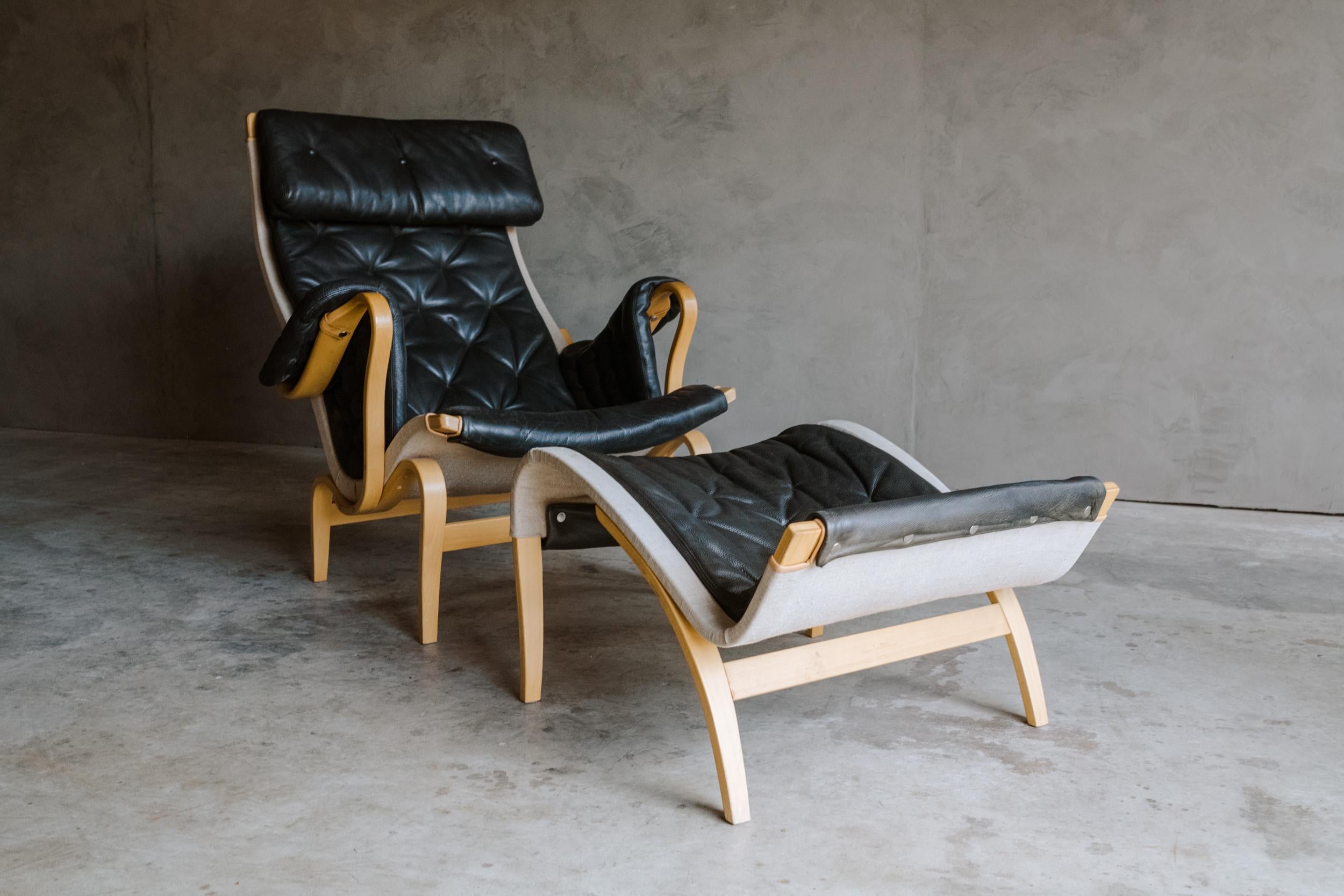 Vintage Bruno Mathsson lounge chair with ottoman, model Pernilla, circa 1970. Original black leather upholstery with very light wear and use. Measures: Ottoman: H - 16 / W - 24.5 / D - 27.
