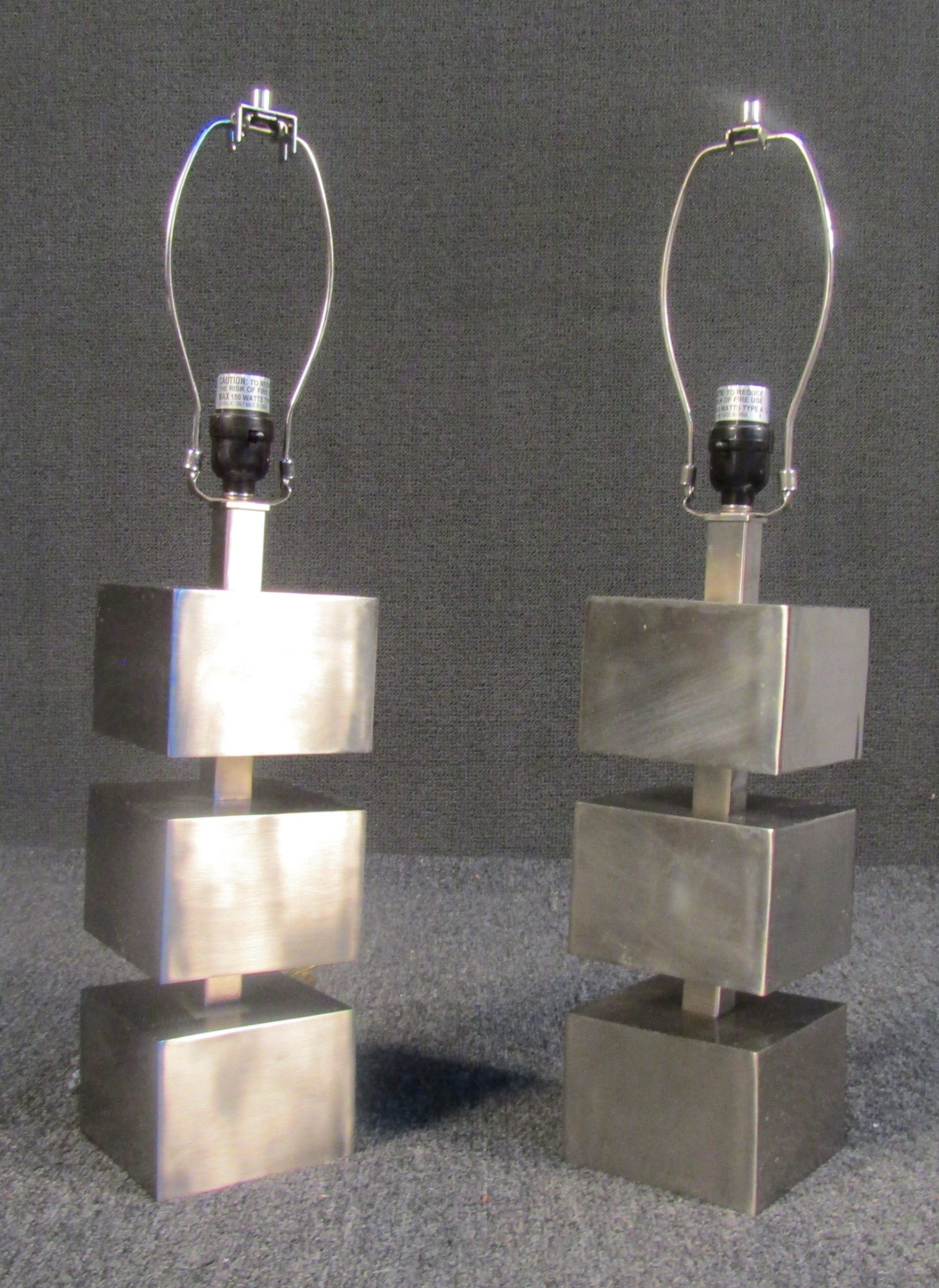 Unique mid-century brushed metal block lamps. These striking lamps provide the perfect blend of industrial aesthetic with the brushed metal, and sleek modern design with the stacked cube forms. These lamps would make a beautiful addition to any