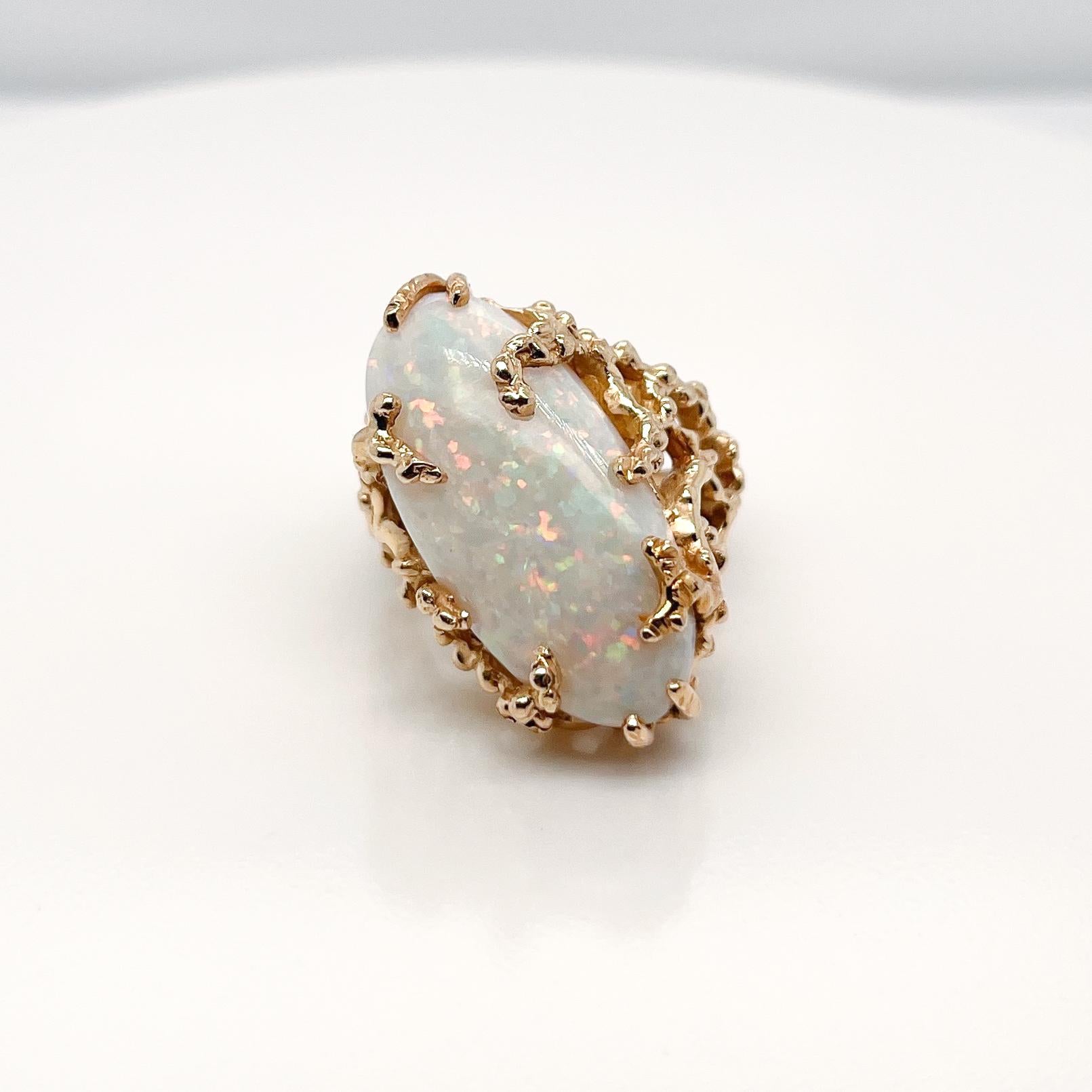 Ein sehr feiner Gold- und Opal-Cocktailring.

Mit einem großen ovalen Opal-Cabochon, der diagonal in einer organischen, gegossenen 18-karätigen Goldfassung gefasst ist.

Einfach ein wunderbarer brutalistischer Ring!

Datum:
20.