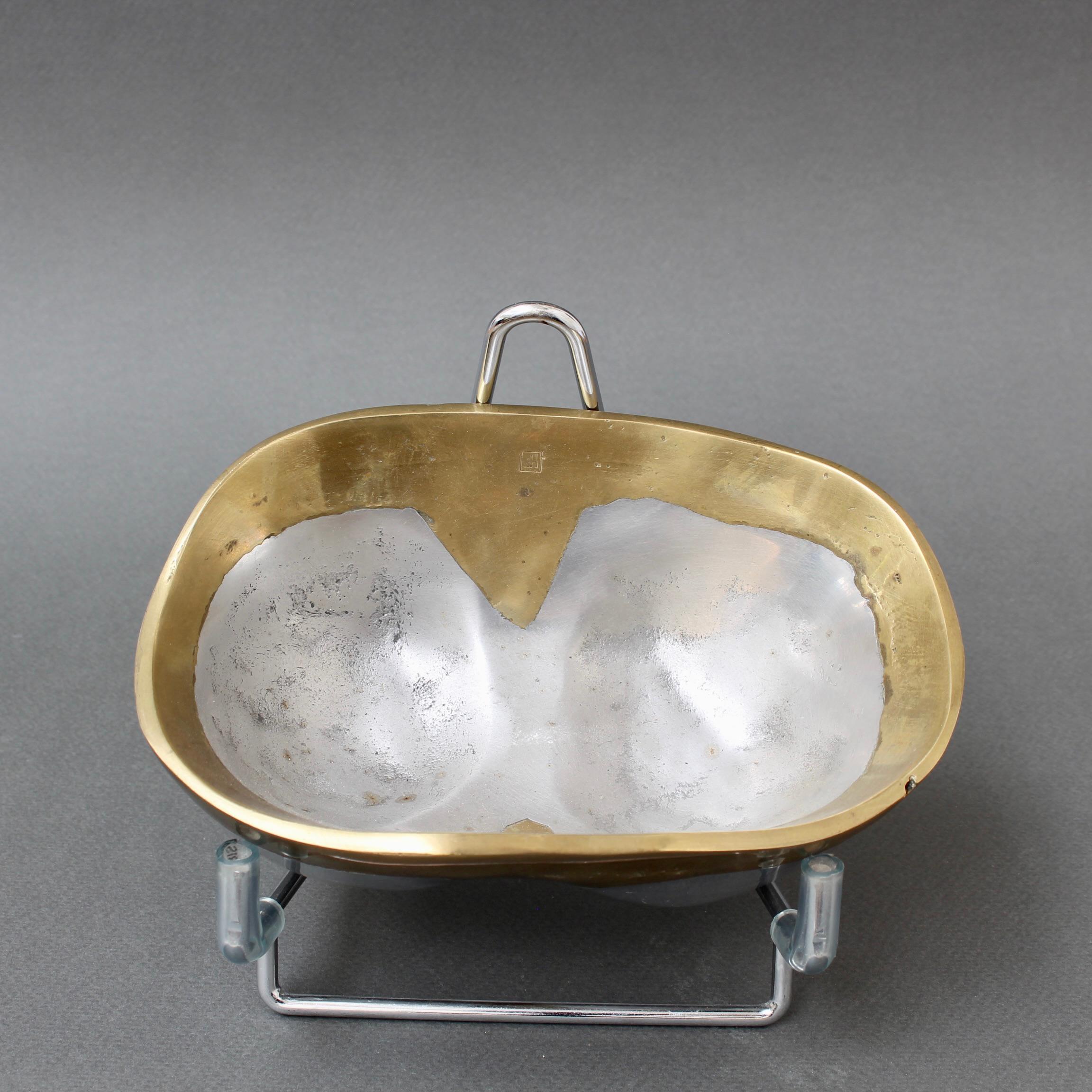A vintage decorative aluminium and brass bowl by David Marshall (circa 1980s). A visually striking piece, Its brutalist solidity and heft are reassuring and its tactility, sensuous. There are two hollows at the bottom making for separate