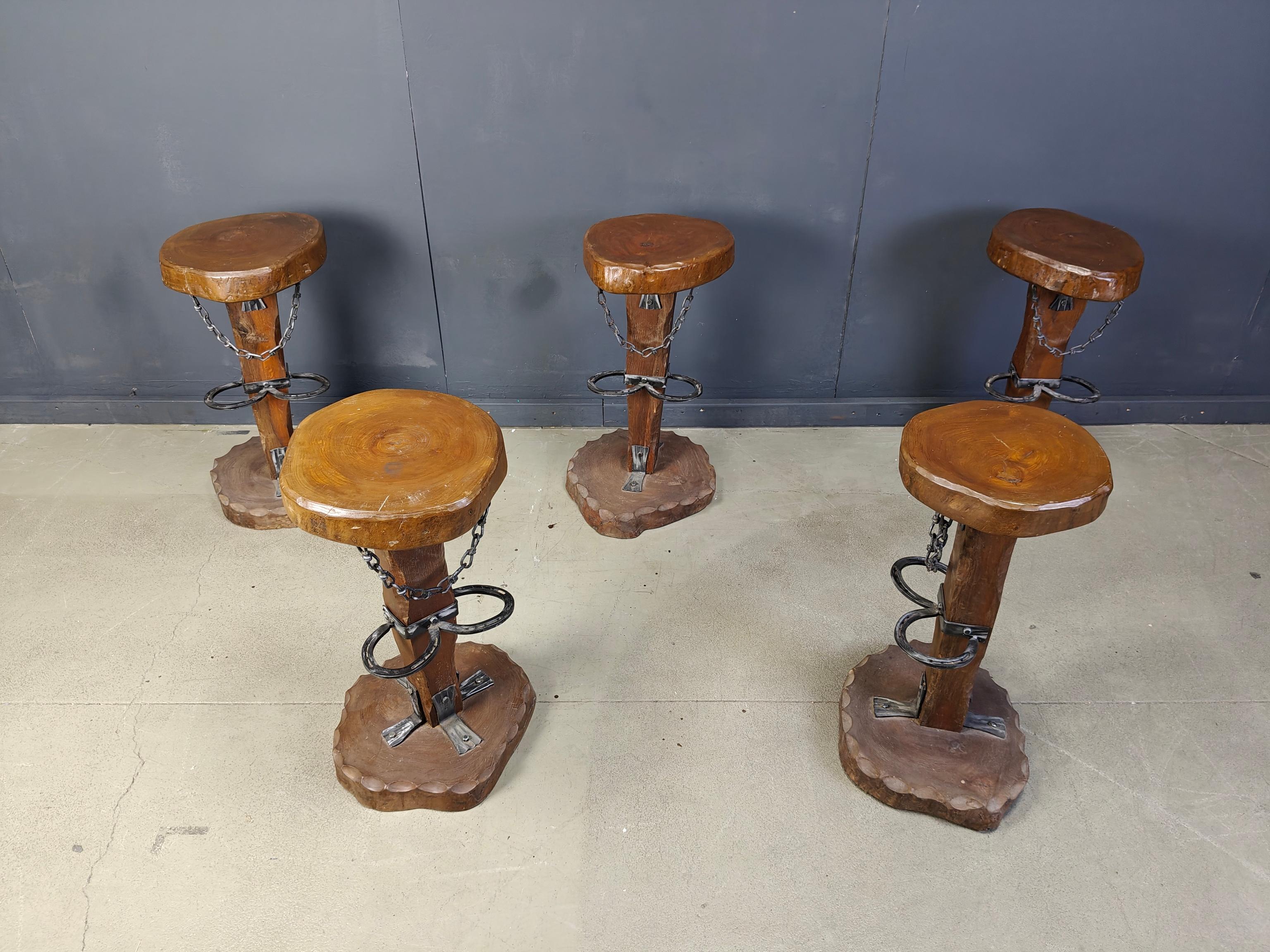 Unique heavy duty bar stools with thick round wooden seats, organic shaped legs and carved wooden bases.

They have steel footrests and other metal hardware. The chains give them an extra heavy duty/inudtsiral look.

Real eye catchers for a bar,