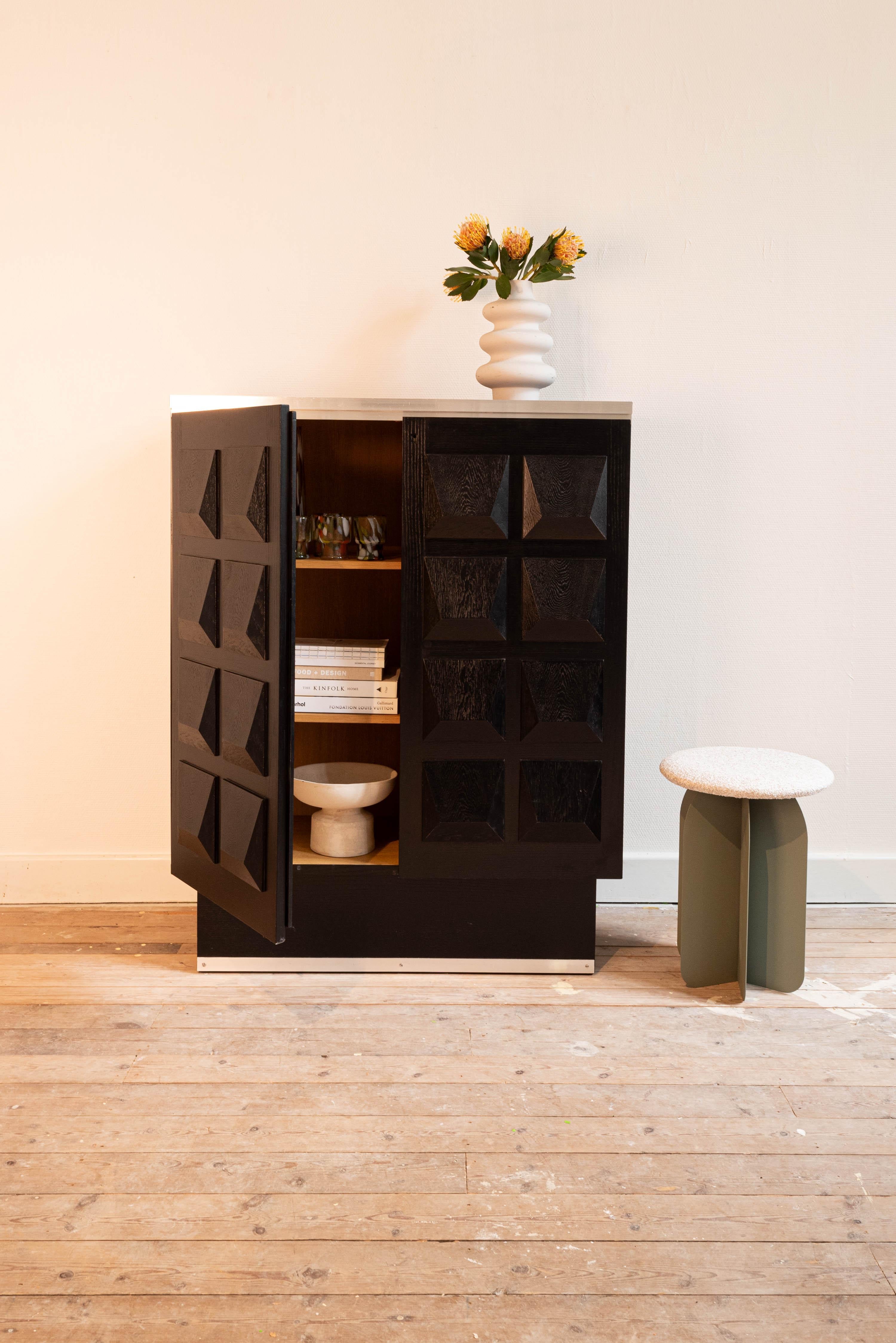 A brutalist De Coene cabinet in black stained oak with two geometric doors, made in Belgium in the 1970s. Behind the diamond pattern doors, this cabinet reveals plenty of storage space, ideal to store and display books, magazines, art and other