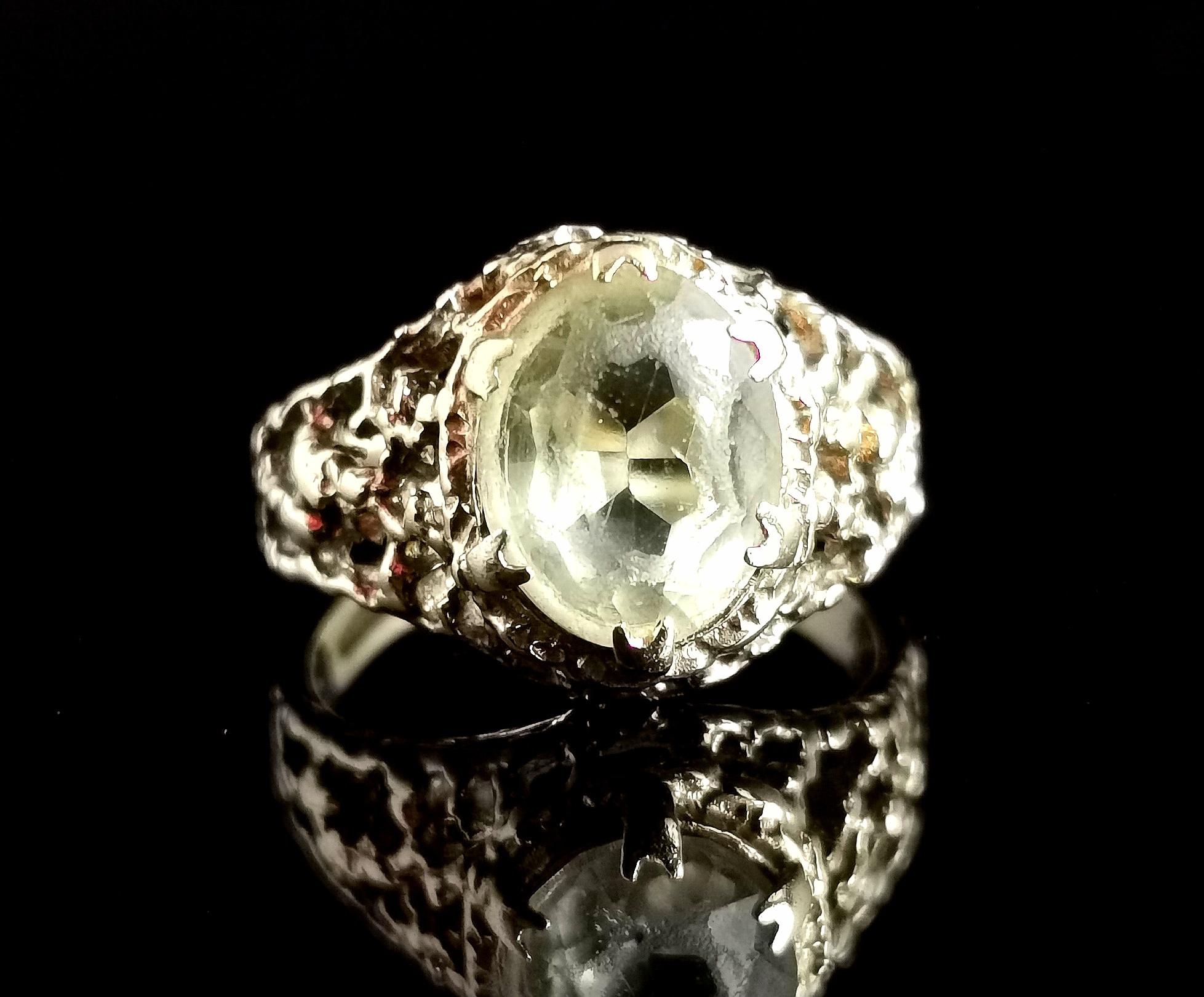 An attractive vintage brutalist style cocktail ring.

This ring has incredible chunky cut out naturalist form shoulders making an almost bombe shape.

It is a large oval cut, light lemony citrine stone which is lightly faceted.

It is a statement