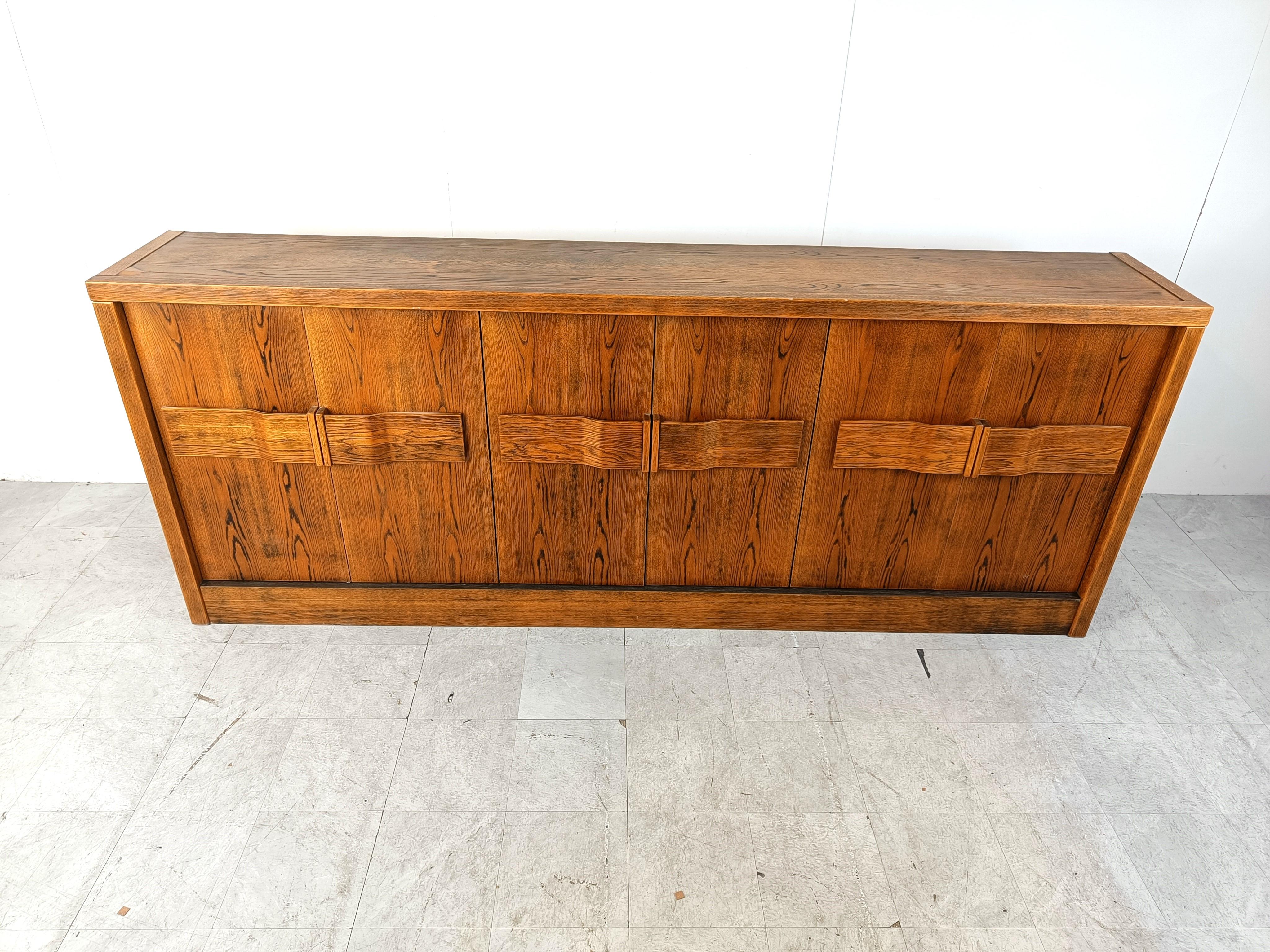 Striking brutalist credenza with large handles.

The credenza has a lot of storage space and features 6 doors.

Good condition, with normal age related wear.

1970s - Belgium

Dimensions:
Height: 110cm
Width: 285cm
Depth: 50cm

Ref.: 90304
