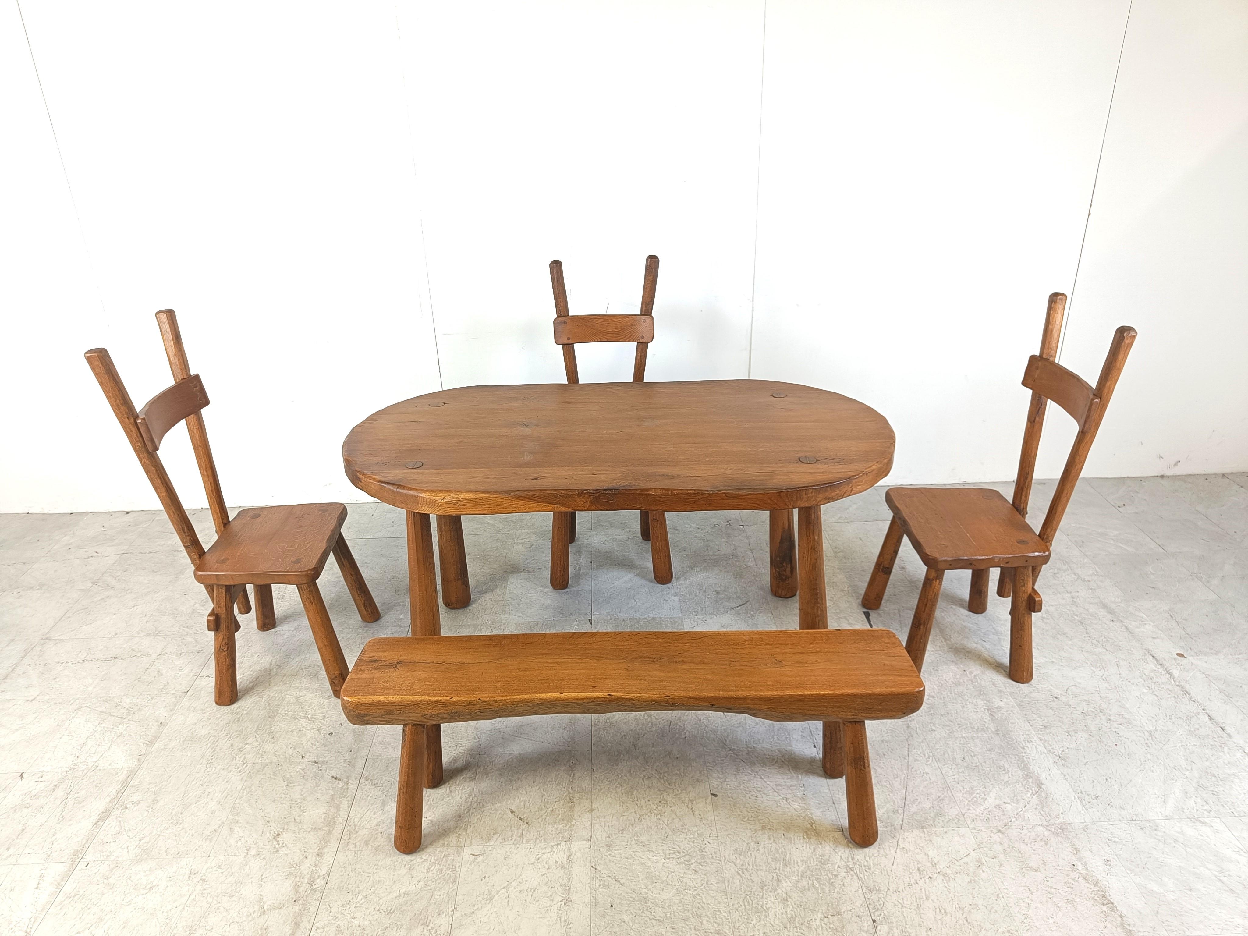 Sturdy and handcrafted dining set with a bench and three high back dining chairs.

This striking design and 'rough' hand made brutalist style is really standing out. 

The entire set is made out of solid oak.

Beautiful split backs with interlocking