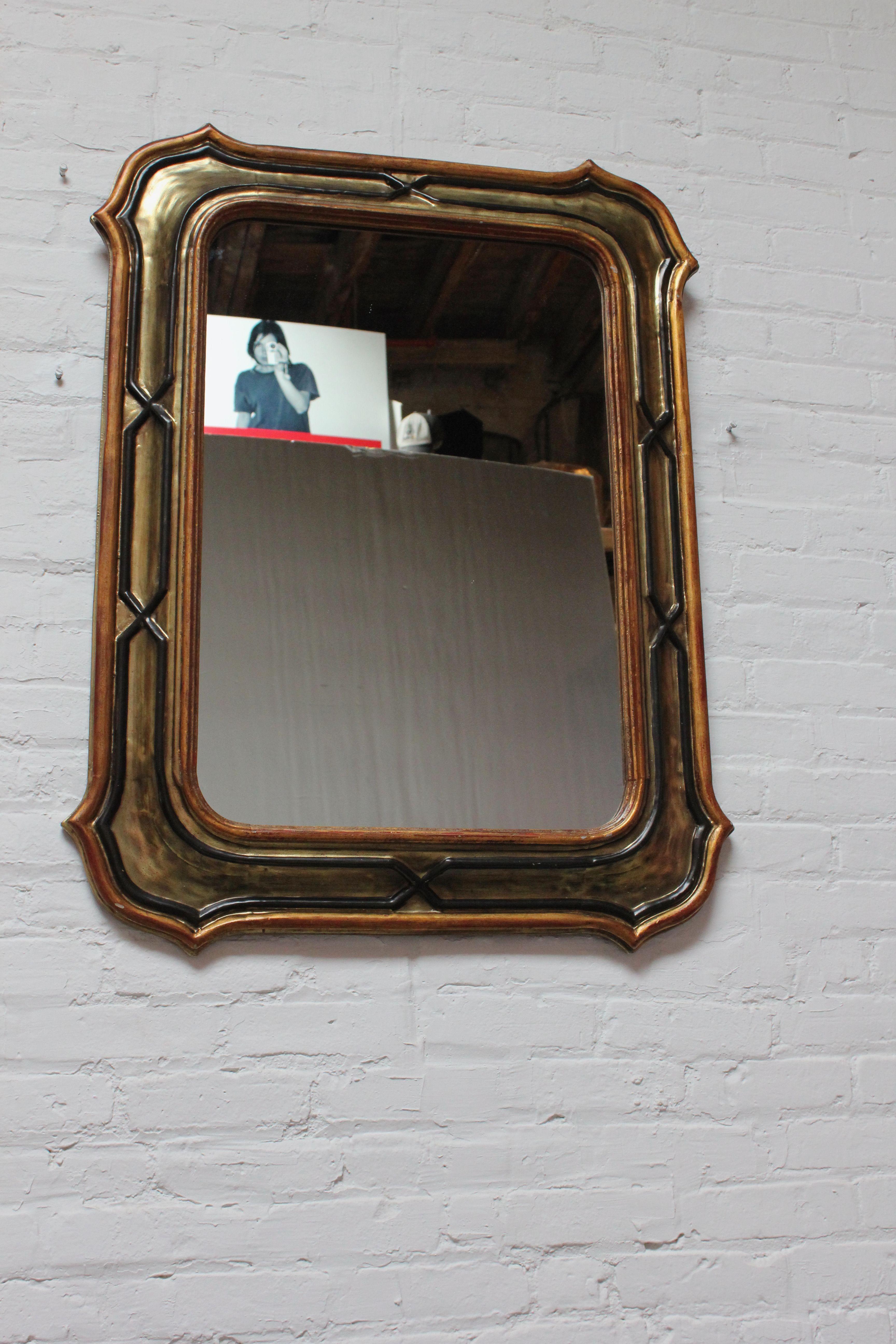 Ornate Brutalist-Style wall mirror composed of resin with gilt and black painted accents (ca. 1970s, USA). Excellent, vintage condition with only light wear present. One of the finials only present in the back has edge loss to the top (not visible
